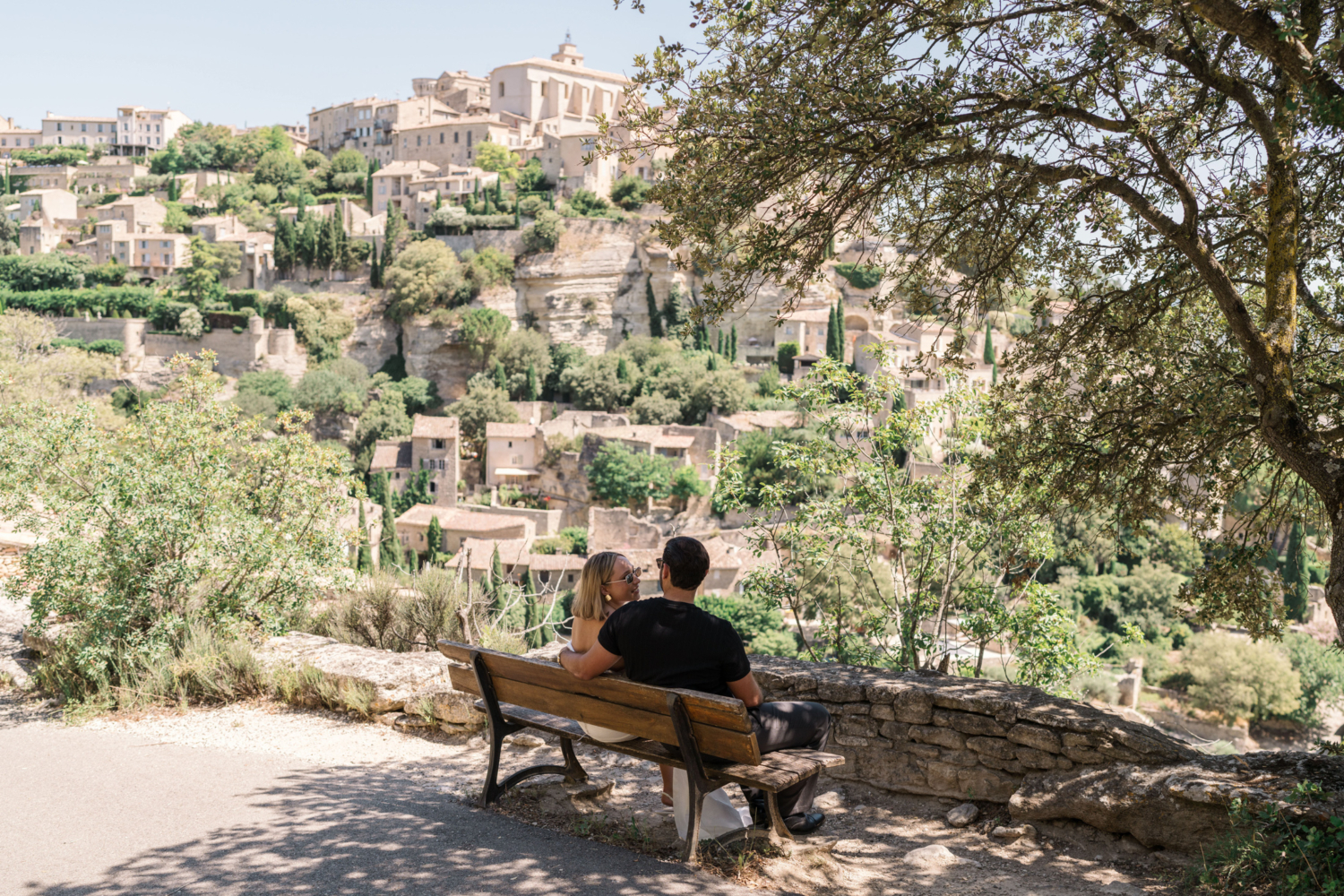 bride and groom relax on bench with view in gordes france