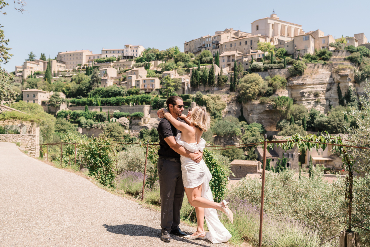 bride and groom pose with gordes in background