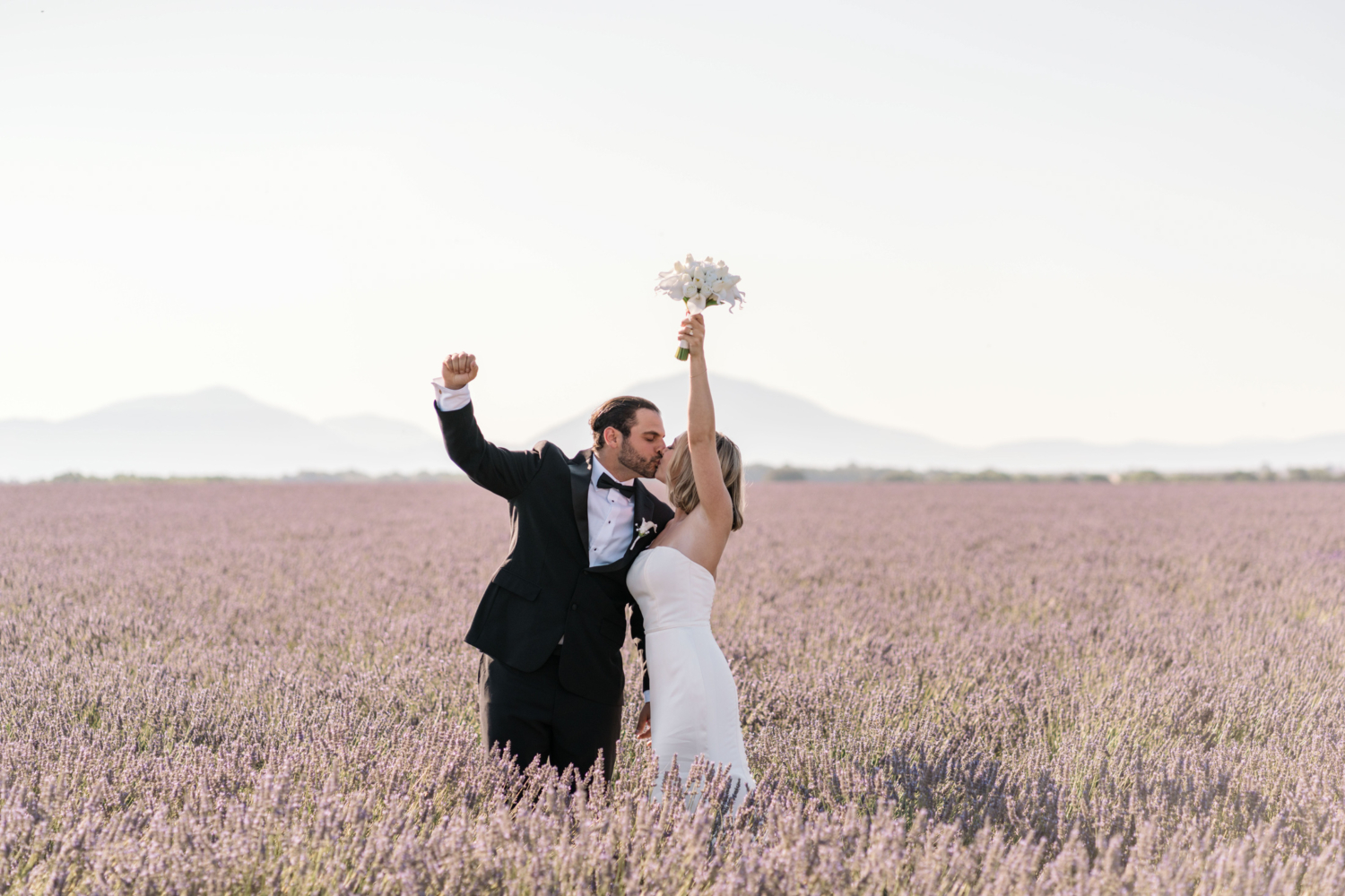 bride and groom kiss and raise fists in air after elopement in lavender field