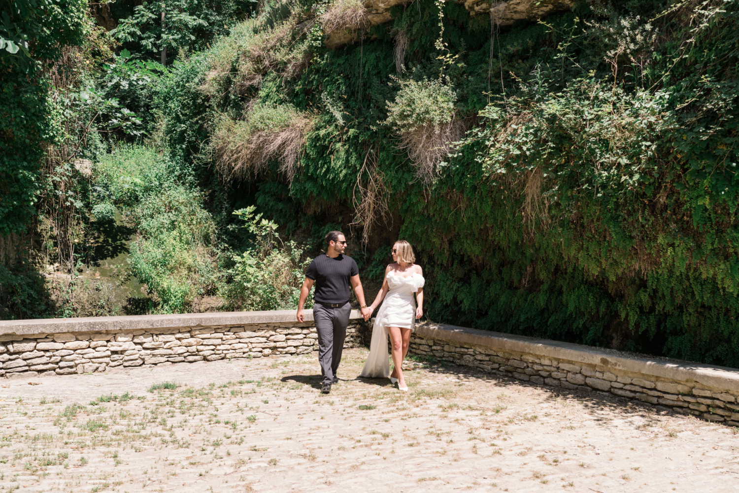 bride and groom walk next to fern wall in gordes france