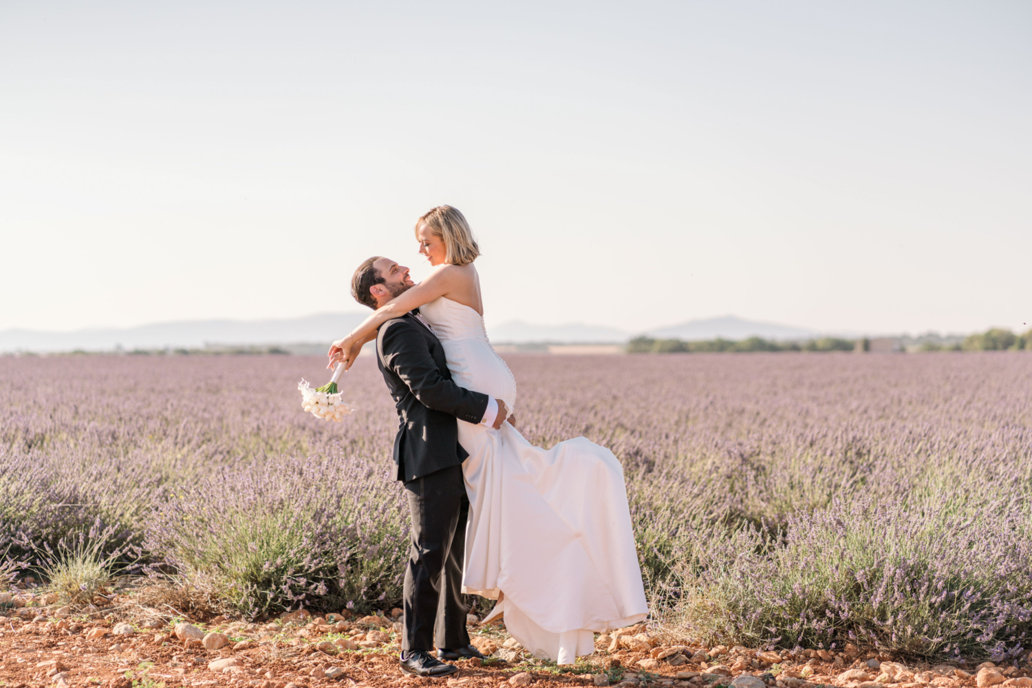 groom lifts bride next to a lavender field in provence