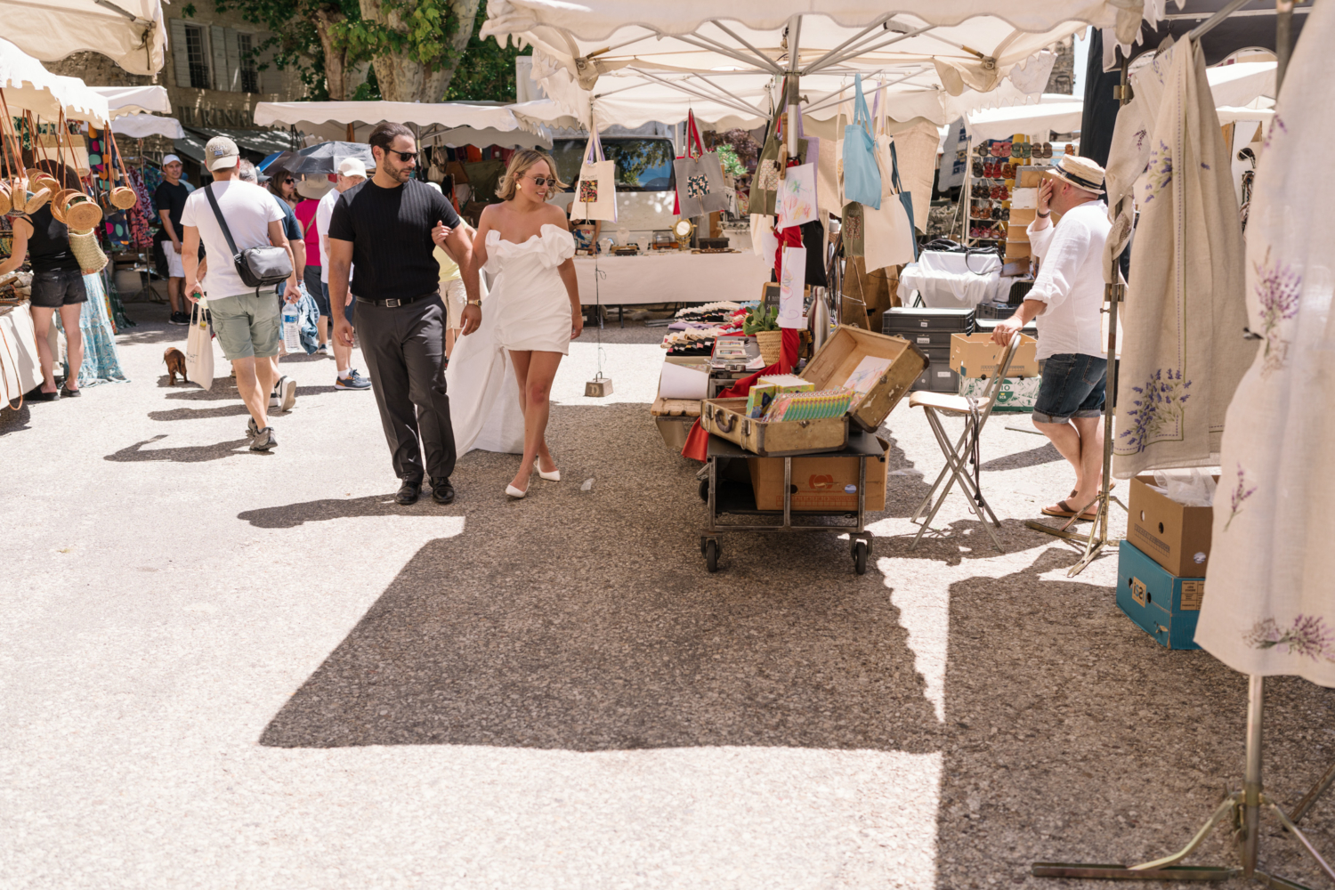 bride and groom have fun walking through market in gordes france