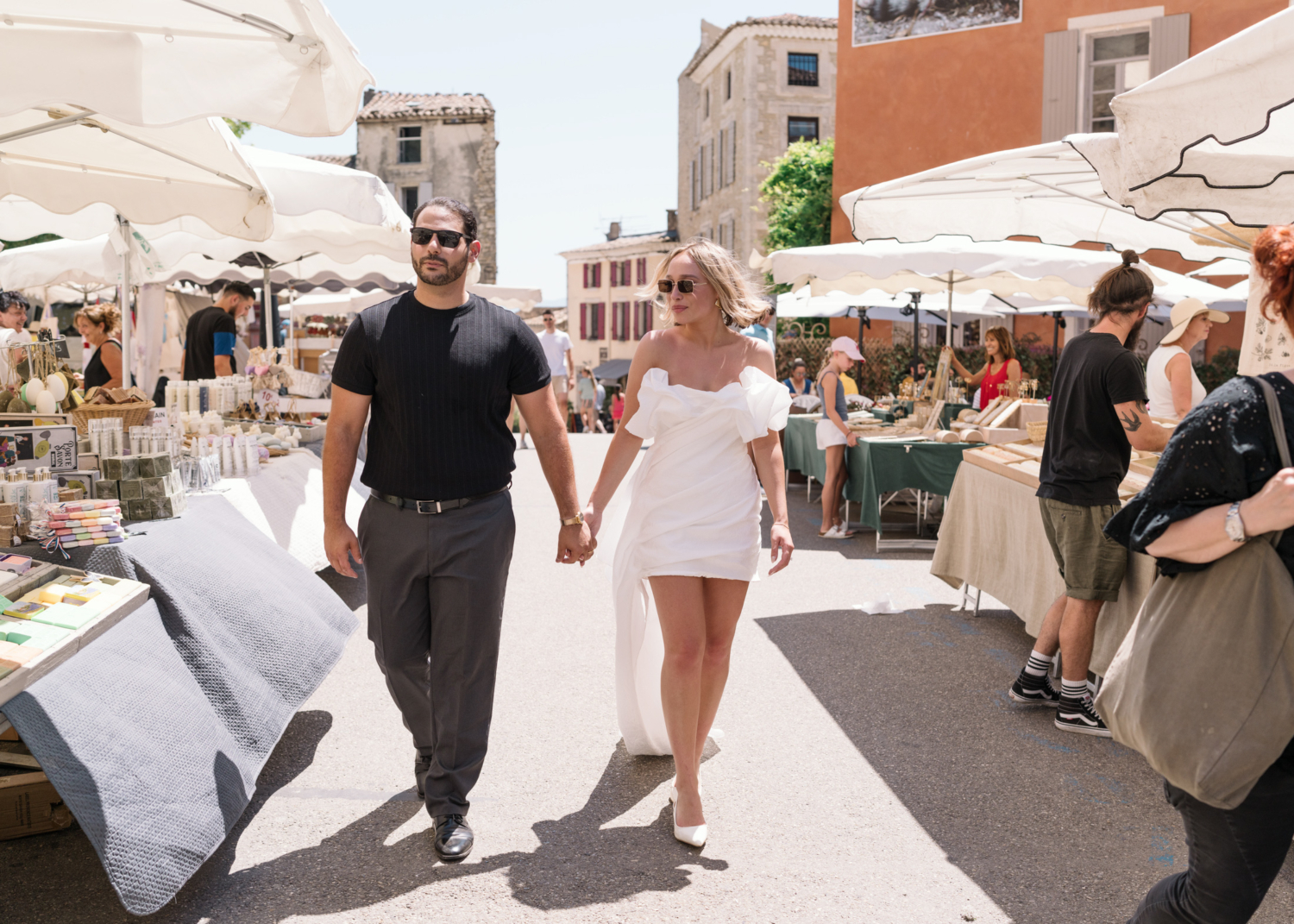 bride and groom walk through weekly market in gordes france