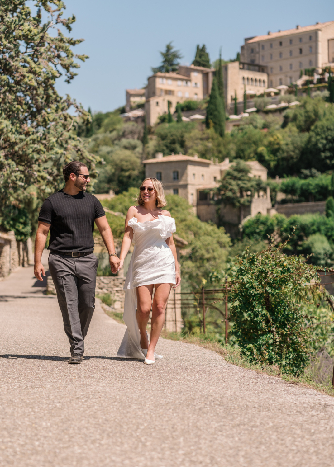 newlyweds walk hand in hand in gordes france