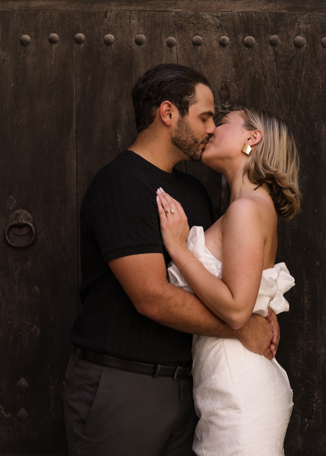 bride and groom kiss in front of brown door in gordes france