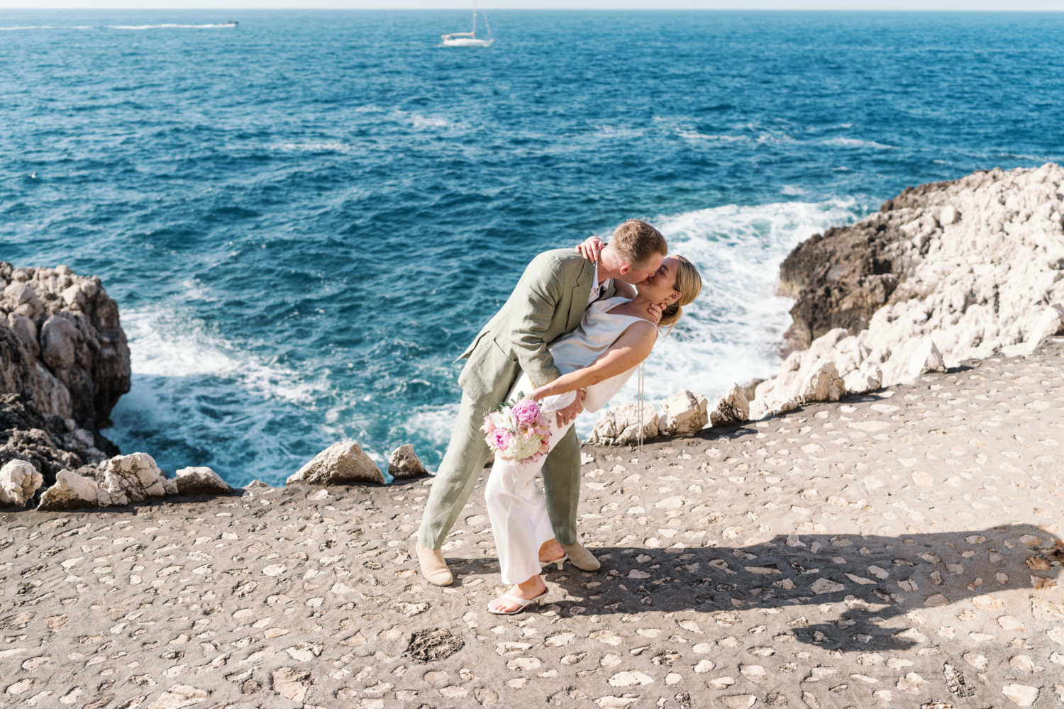 groom dips bride and kisses her on french riviera