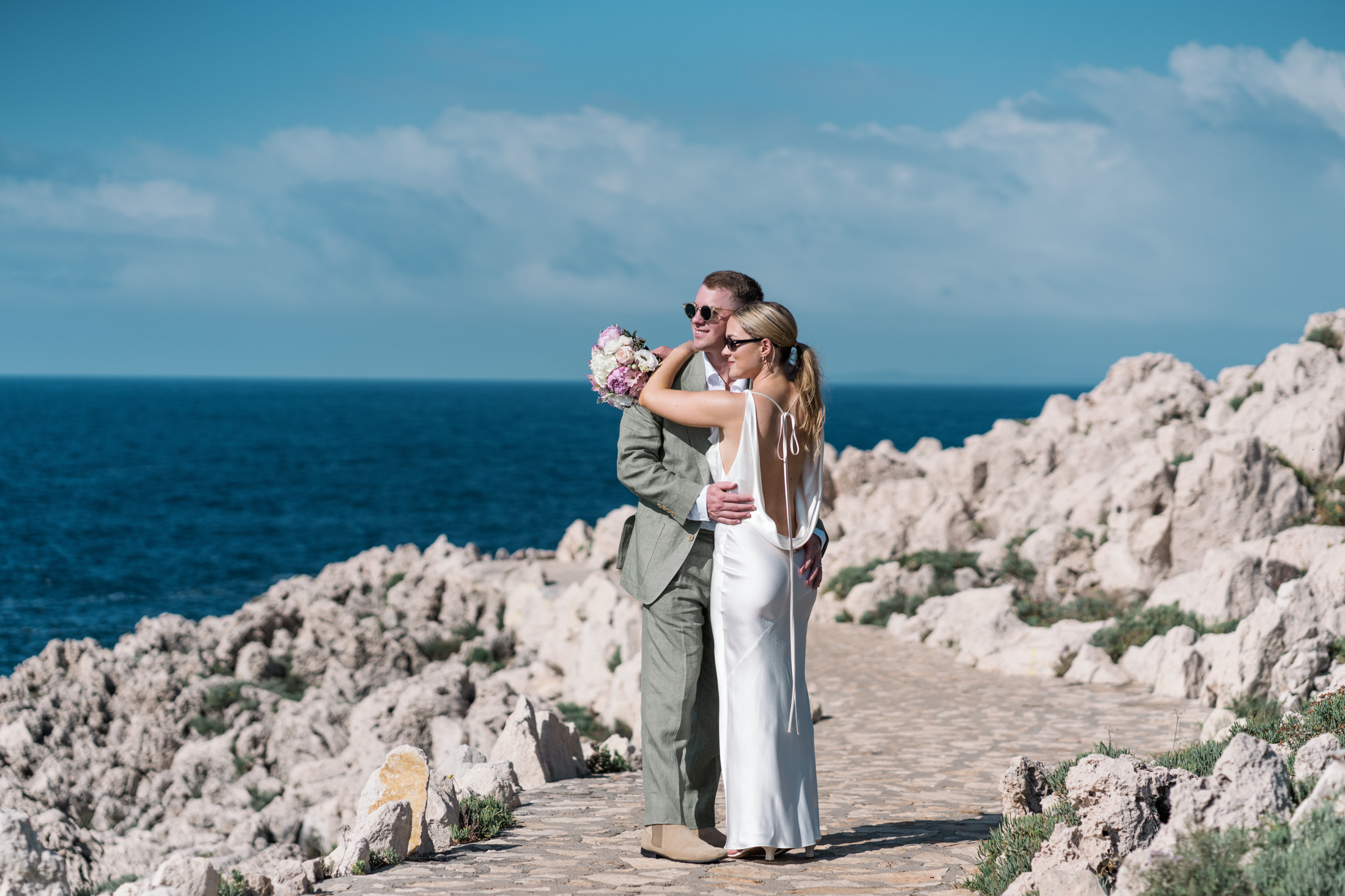 bride and groom pose next to sea in saint jean cap ferrat