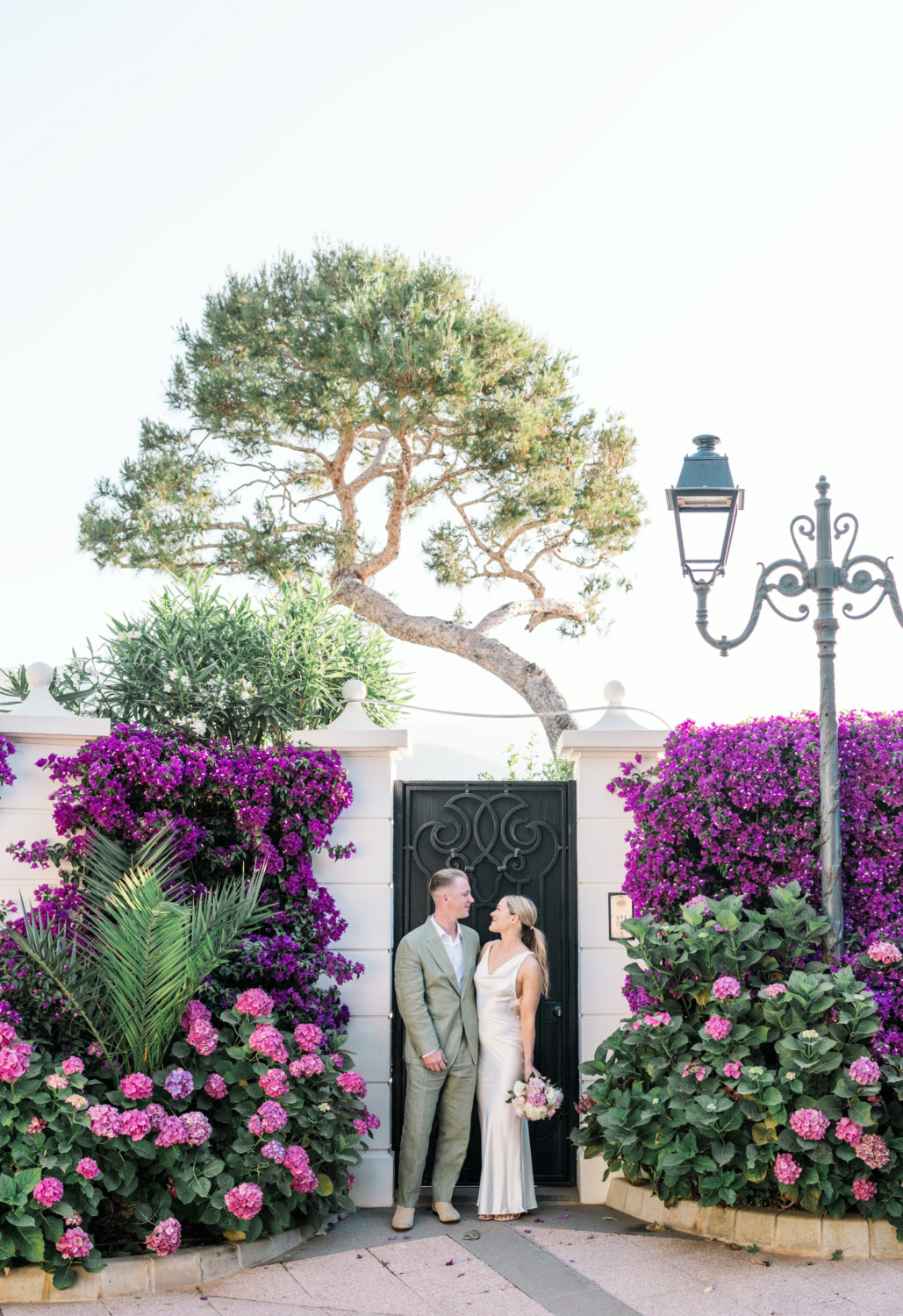 bride and groom pose in front of flowered door in saint jean cap ferrat