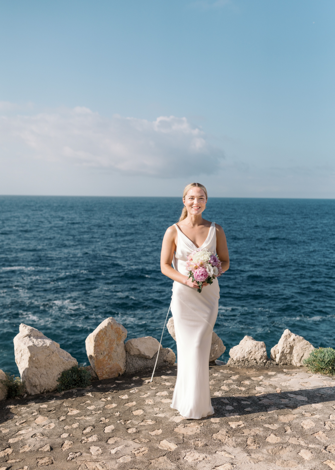 bride poses with flower bouquet on french riviera