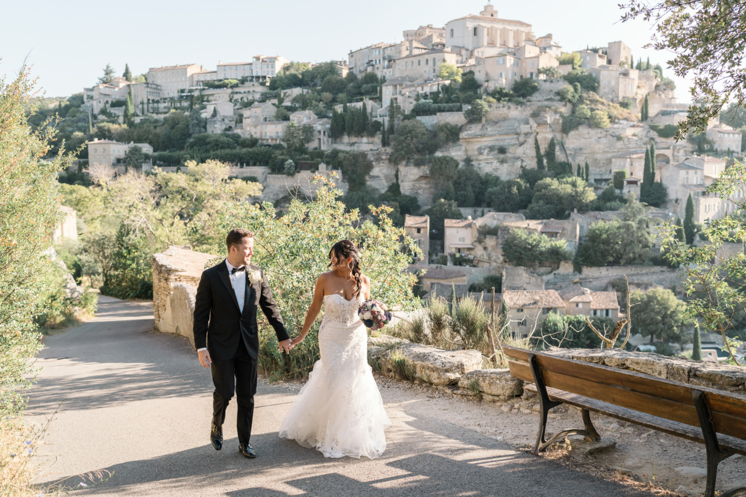 bride and groom walk hand in hand in gordes france