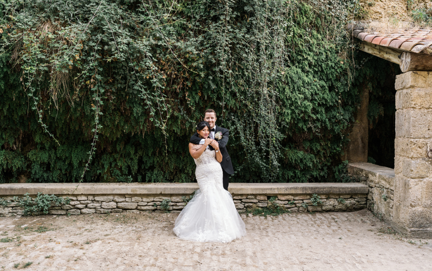 bride and groom embrace in old gordes france near fern wall