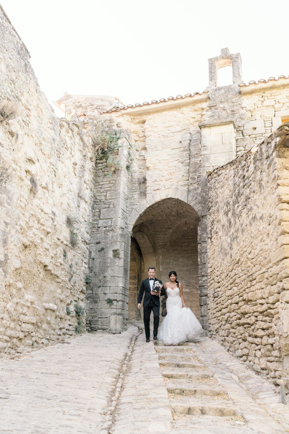 bride and groom walk down medieval staircase in gordes france