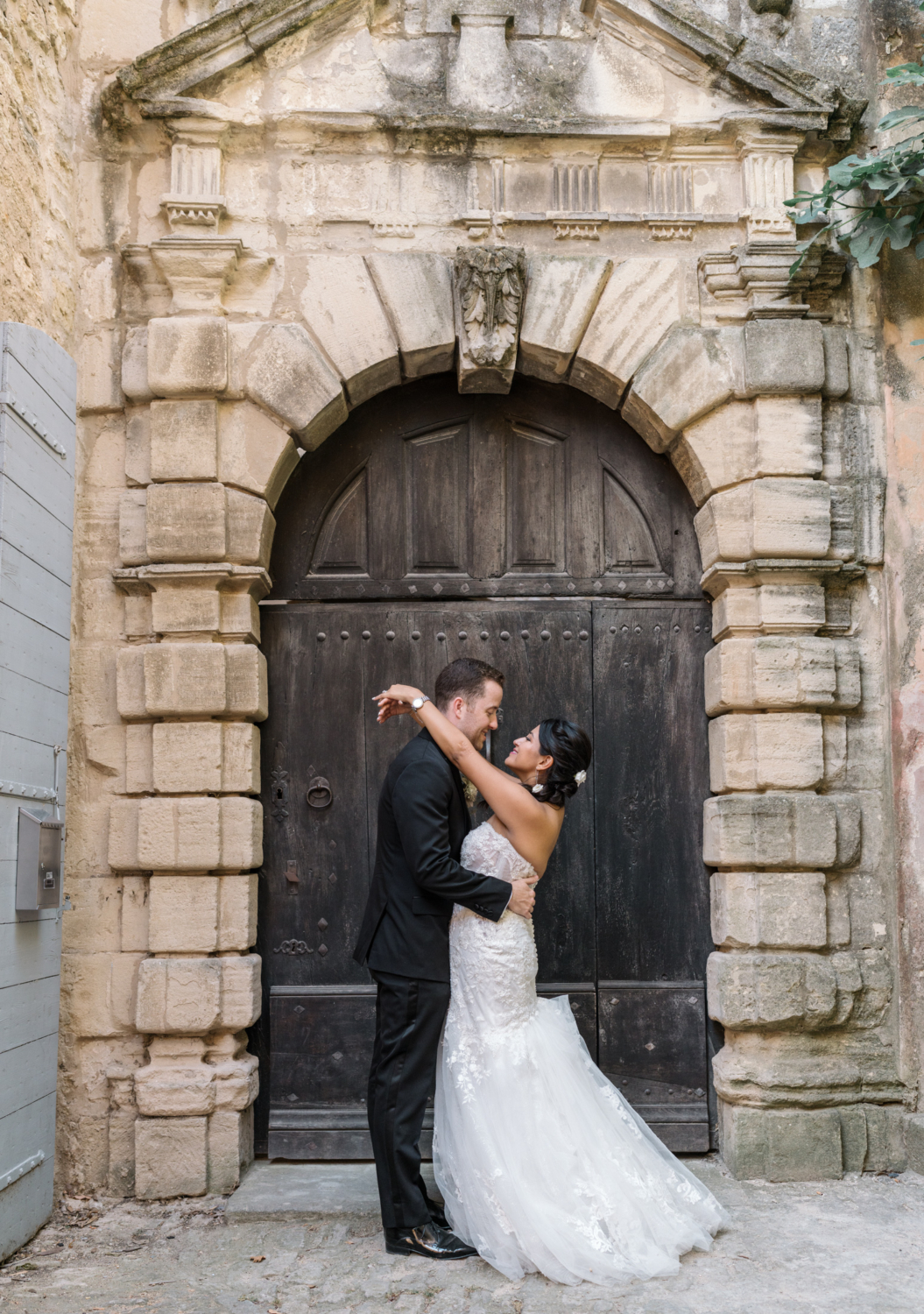 newlyweds hug in front of brown door in gordes france