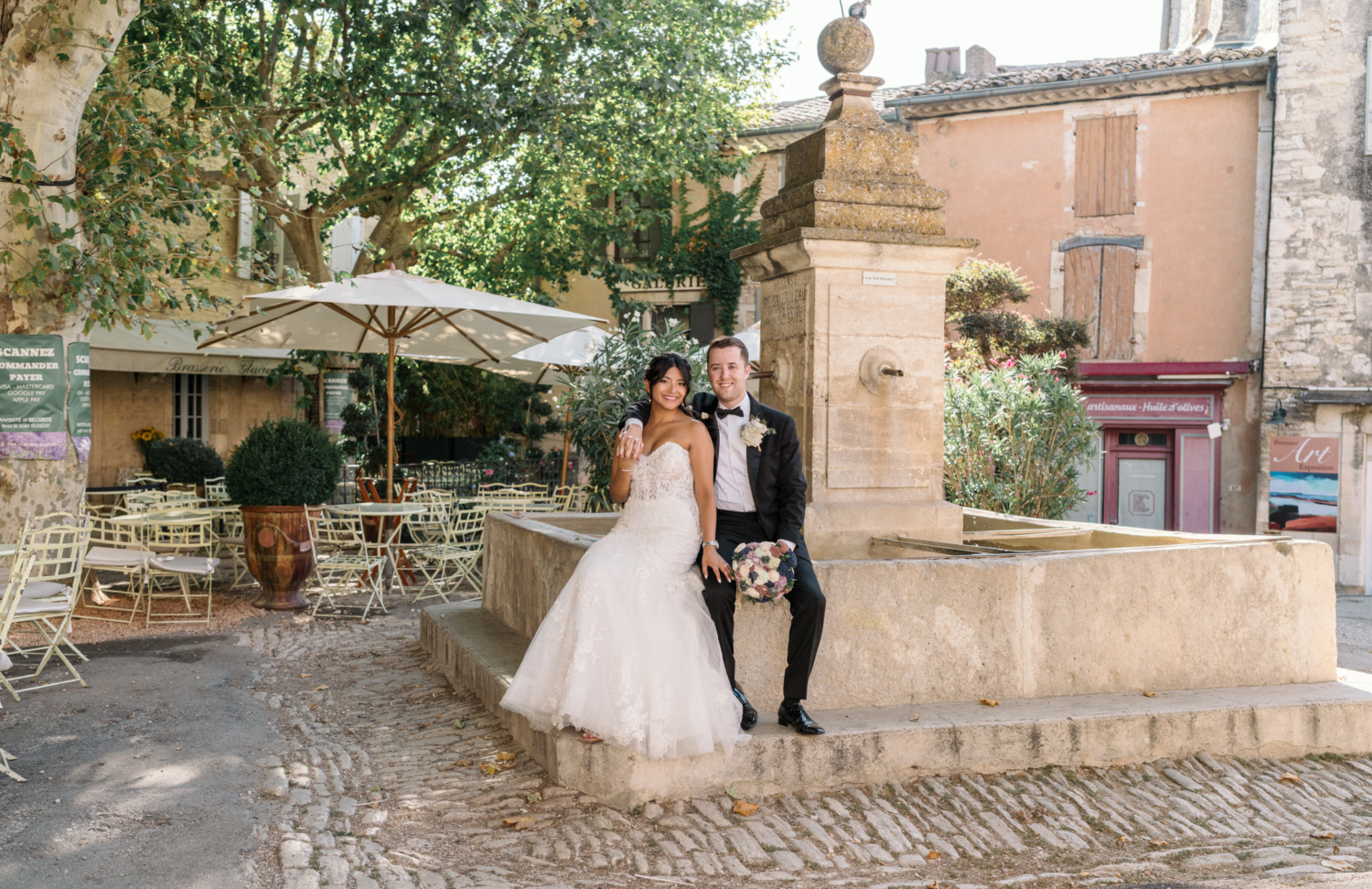 bride and groom pose at old fountain in gordes france