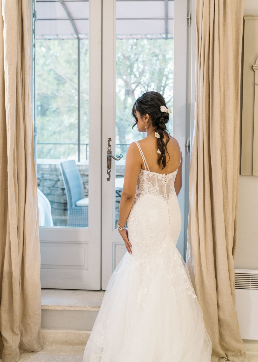 bride looks out window on her wedding day in gordes france