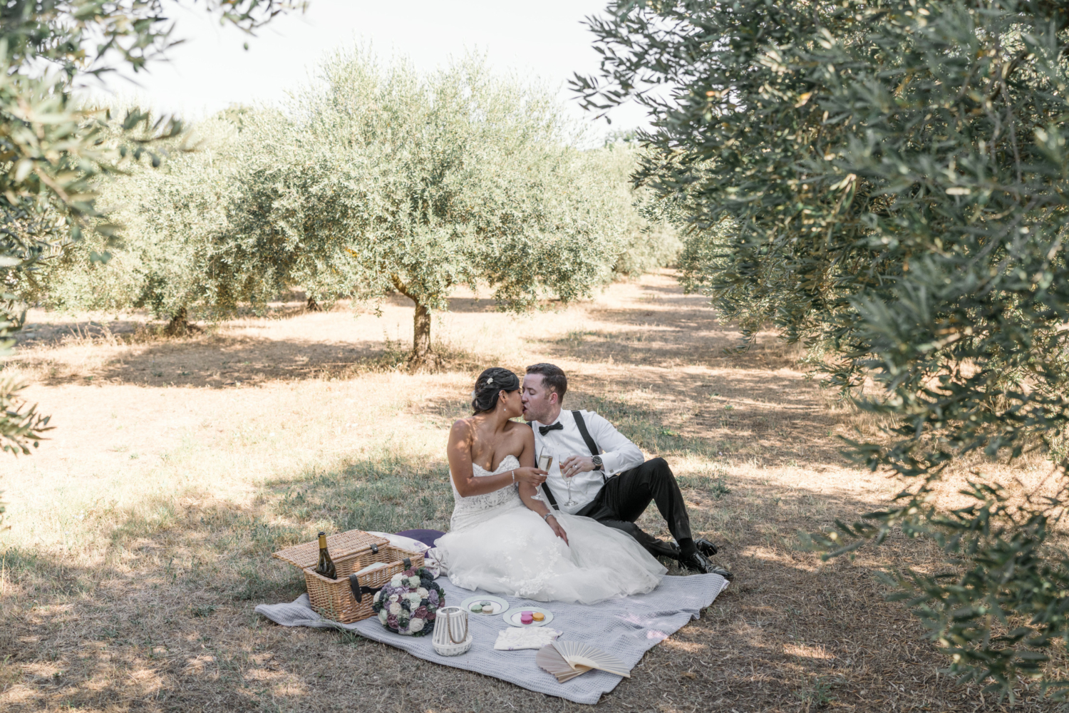 bride and groom kiss at picnic in olive groves in gordes france