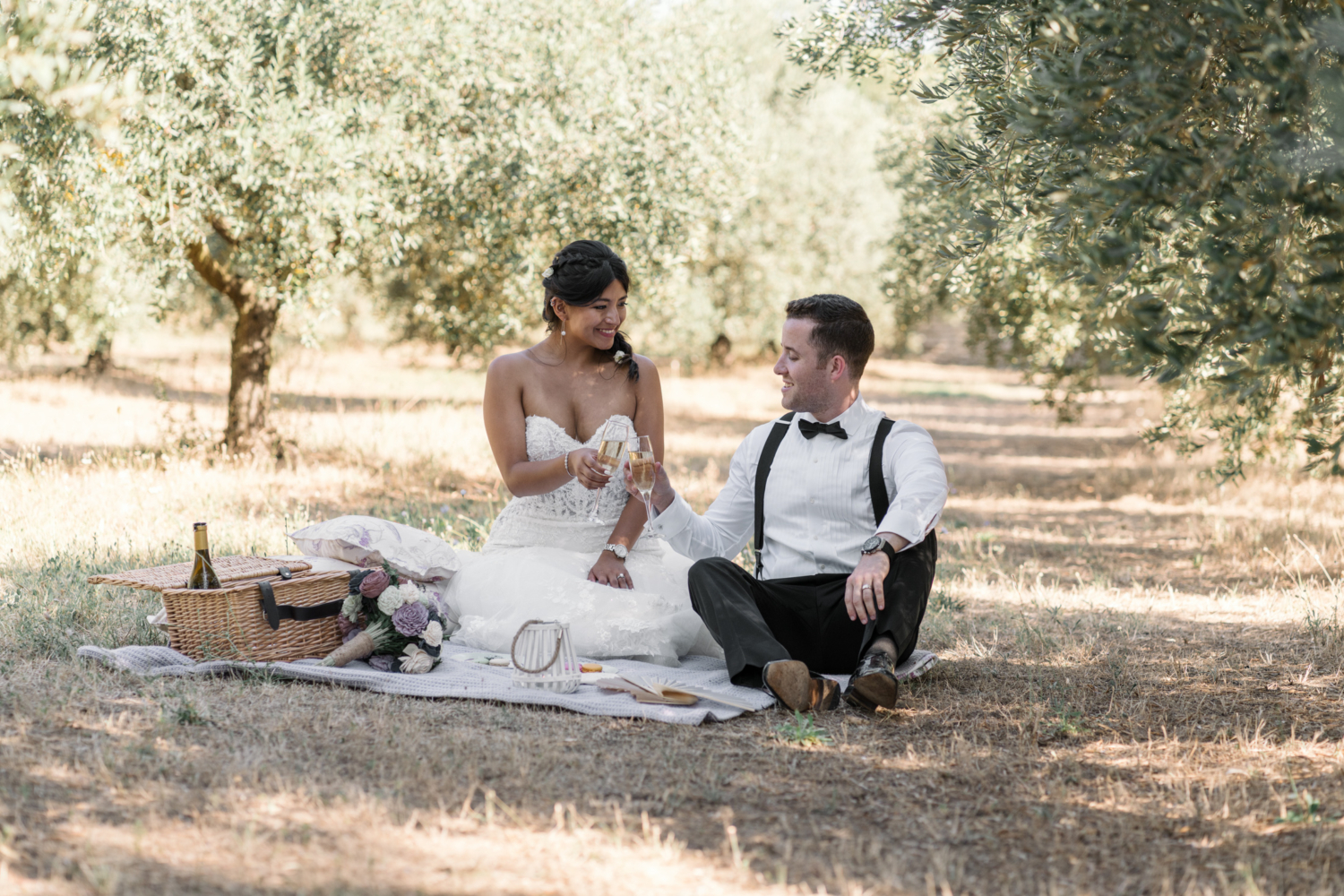 bride and groom toast each other at picnic in olive grove