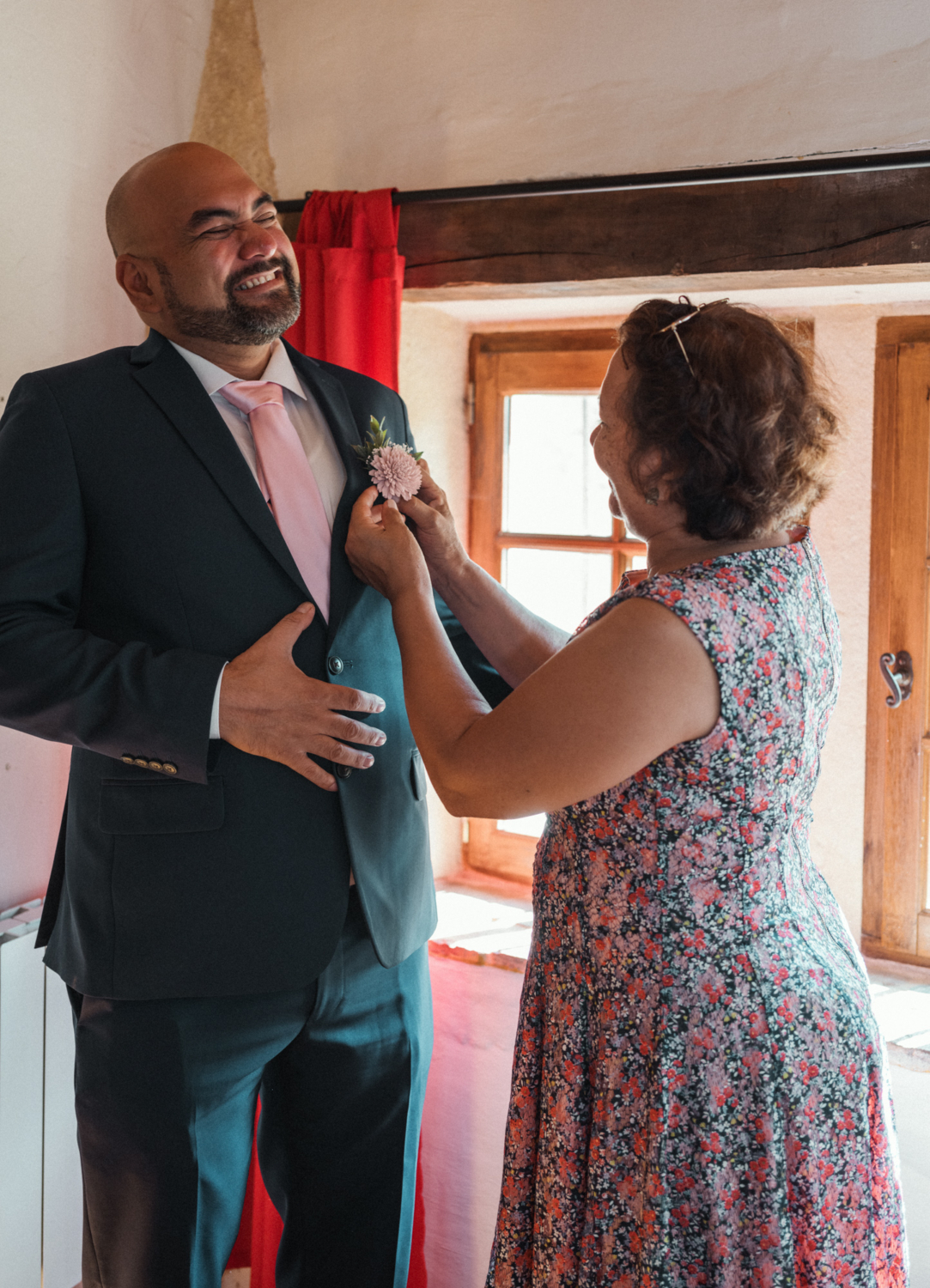 mother pins flower to grooms suit before wedding