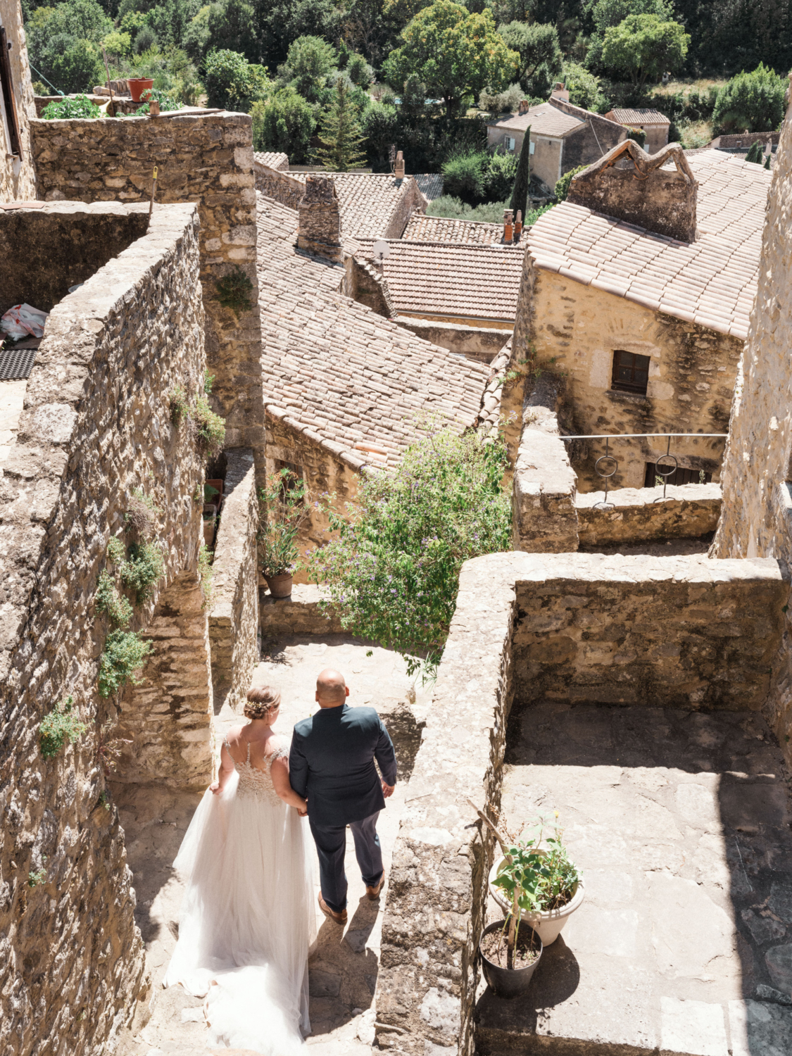bride and groom walk hand in hand in medieval french village