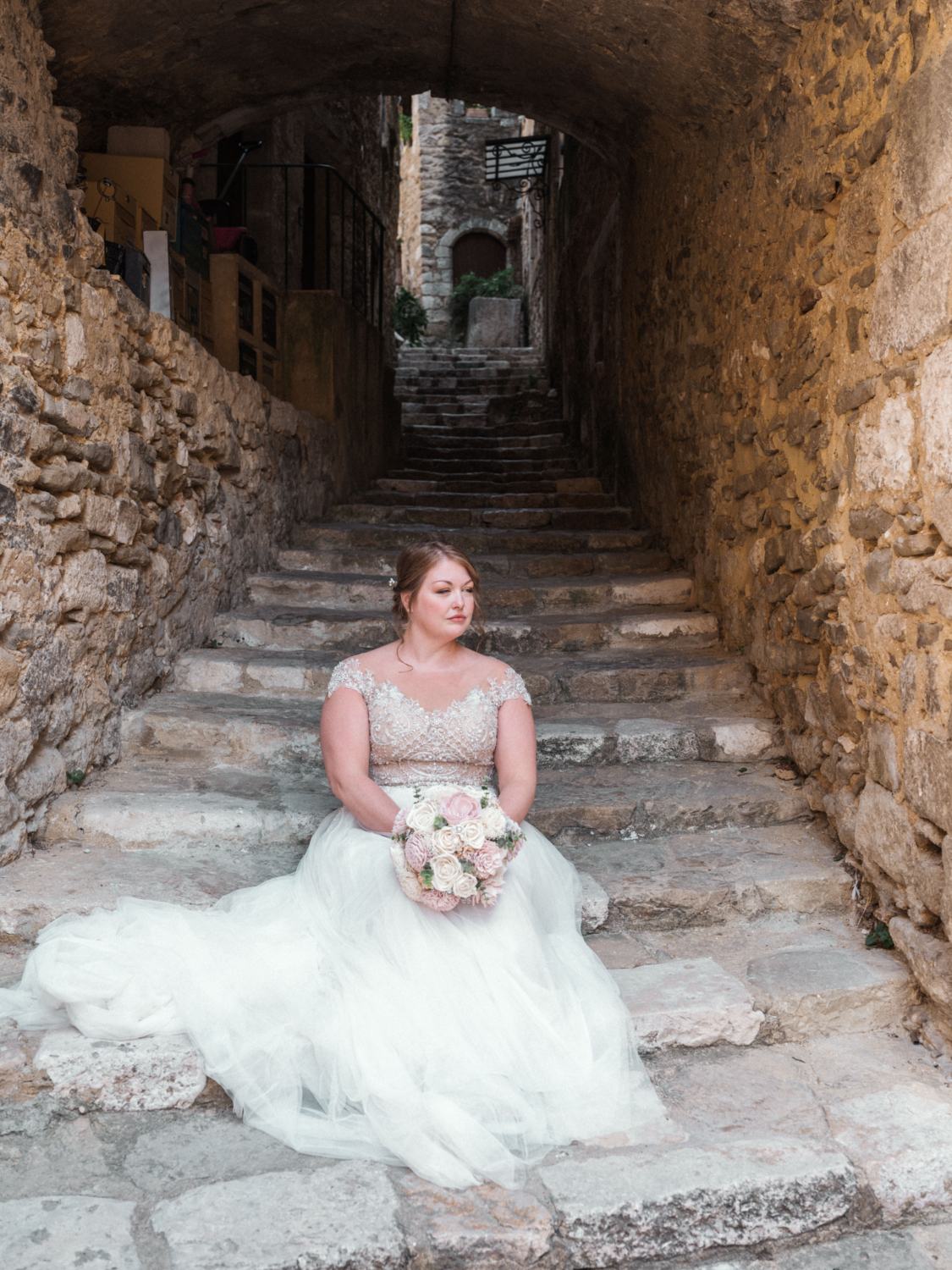 bride poses on medieval steps before her wedding