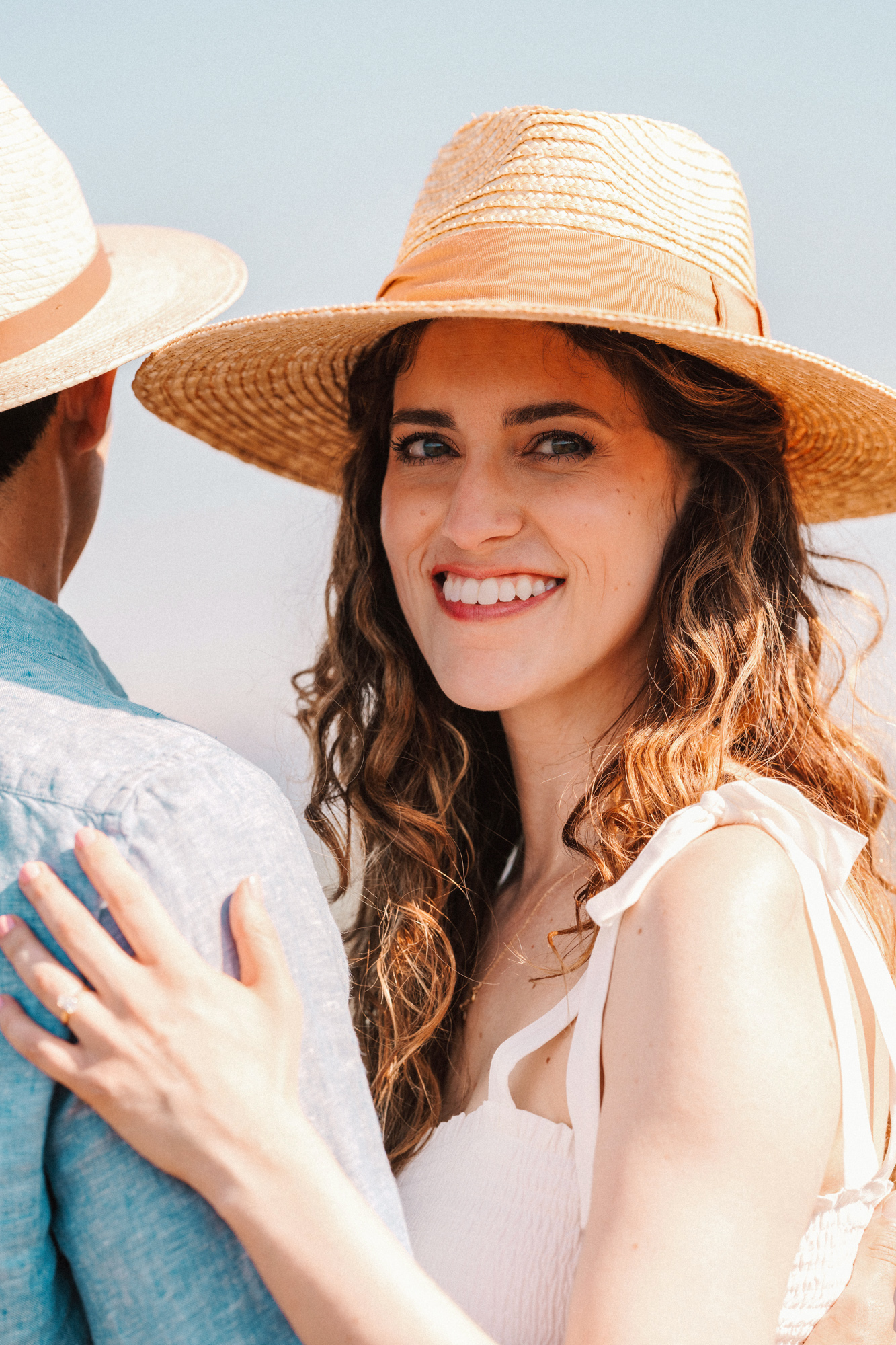 newly engaged woman in hat smiles