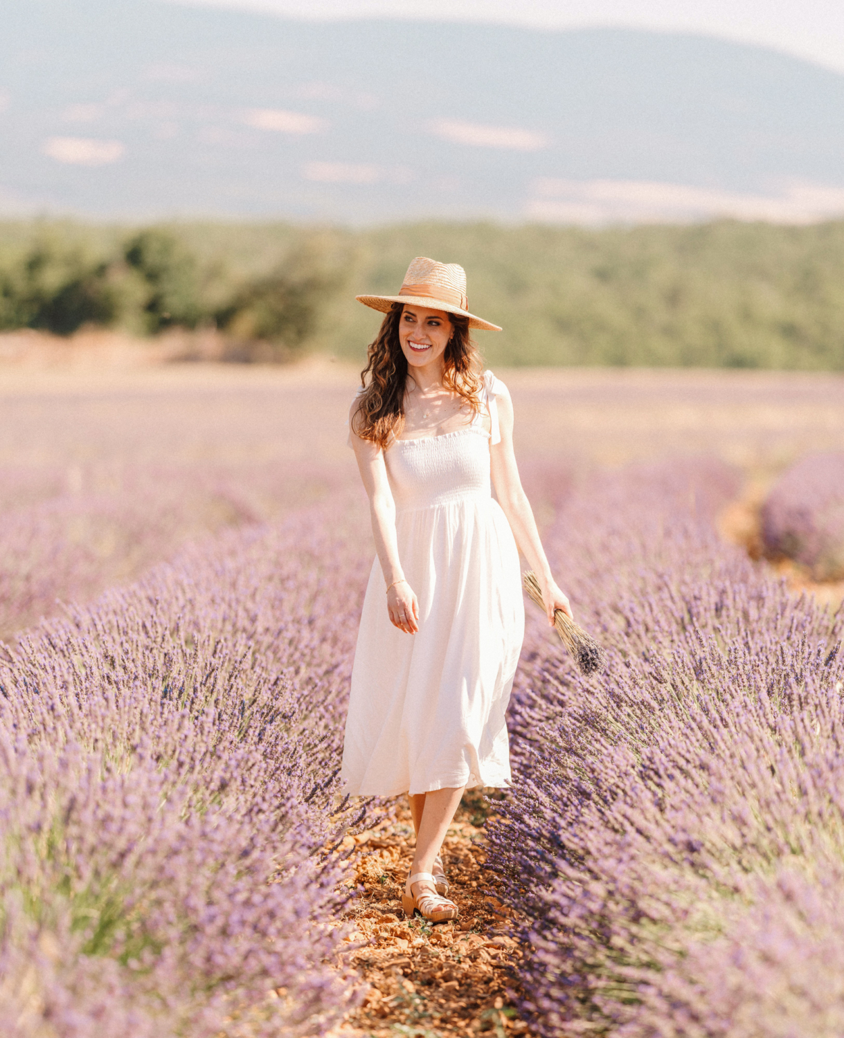 woman walks in lavender field wearing hat