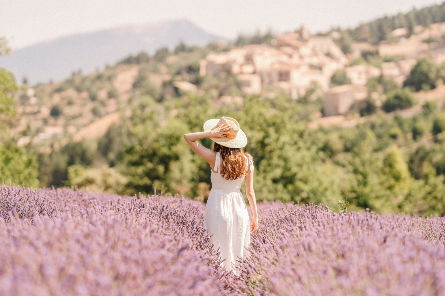 red haired woman touches hat in lavender field