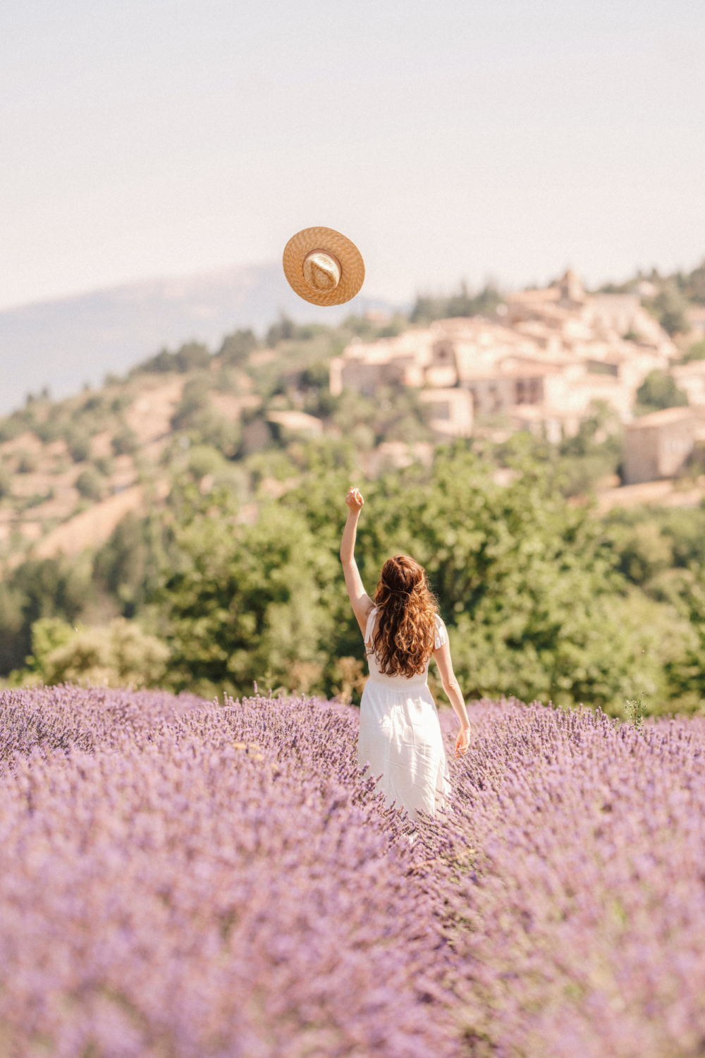 woman throws hat in lavender field