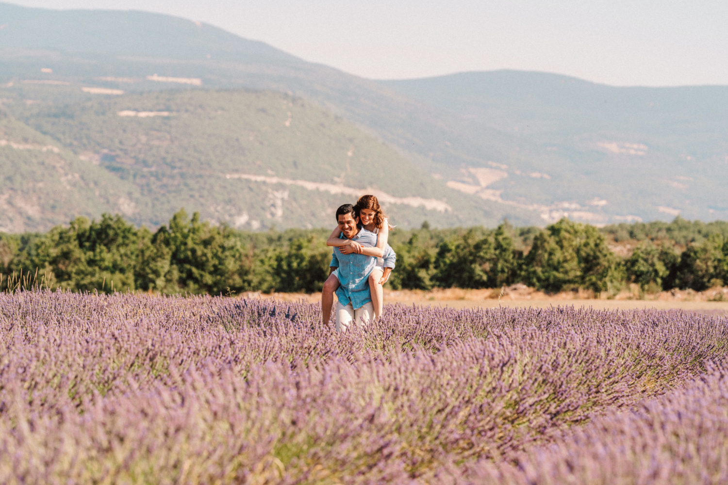 man gives woman piggy back ride through lavender field