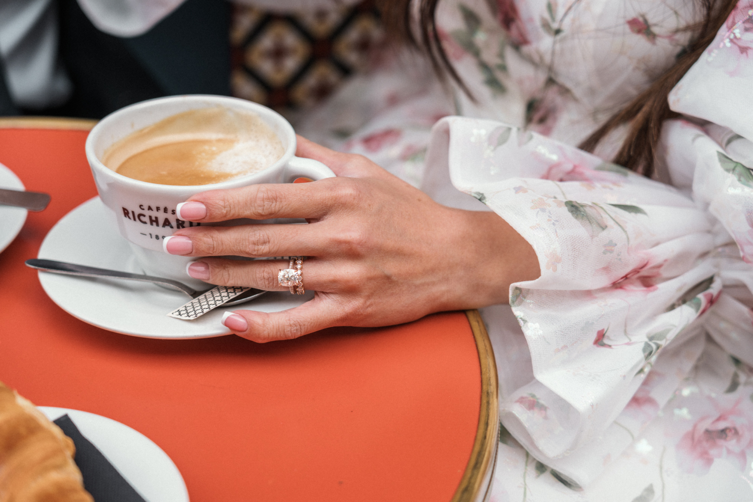 woman holds coffee showing diamond wedding ring in paris