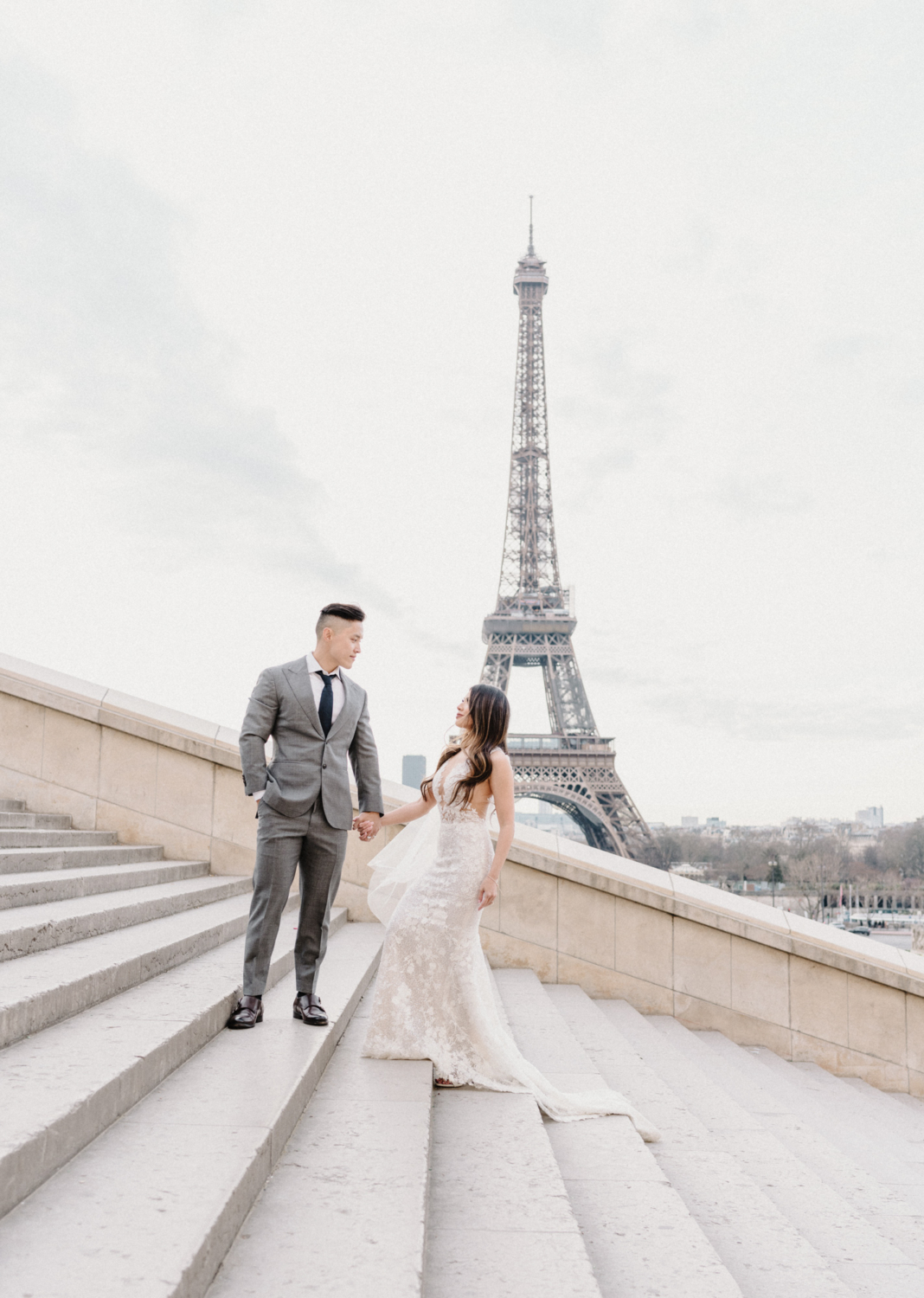 asian wedding couple walking up staircase with eiffel tower view