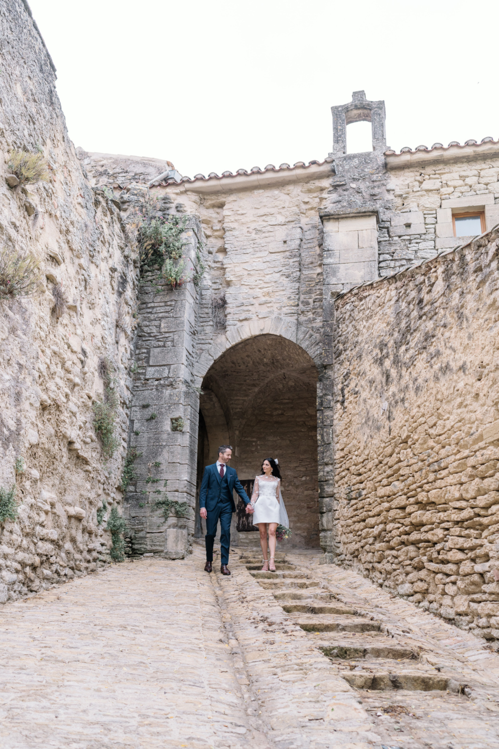 bride and groom walk down cobblestone staircase in gordes france