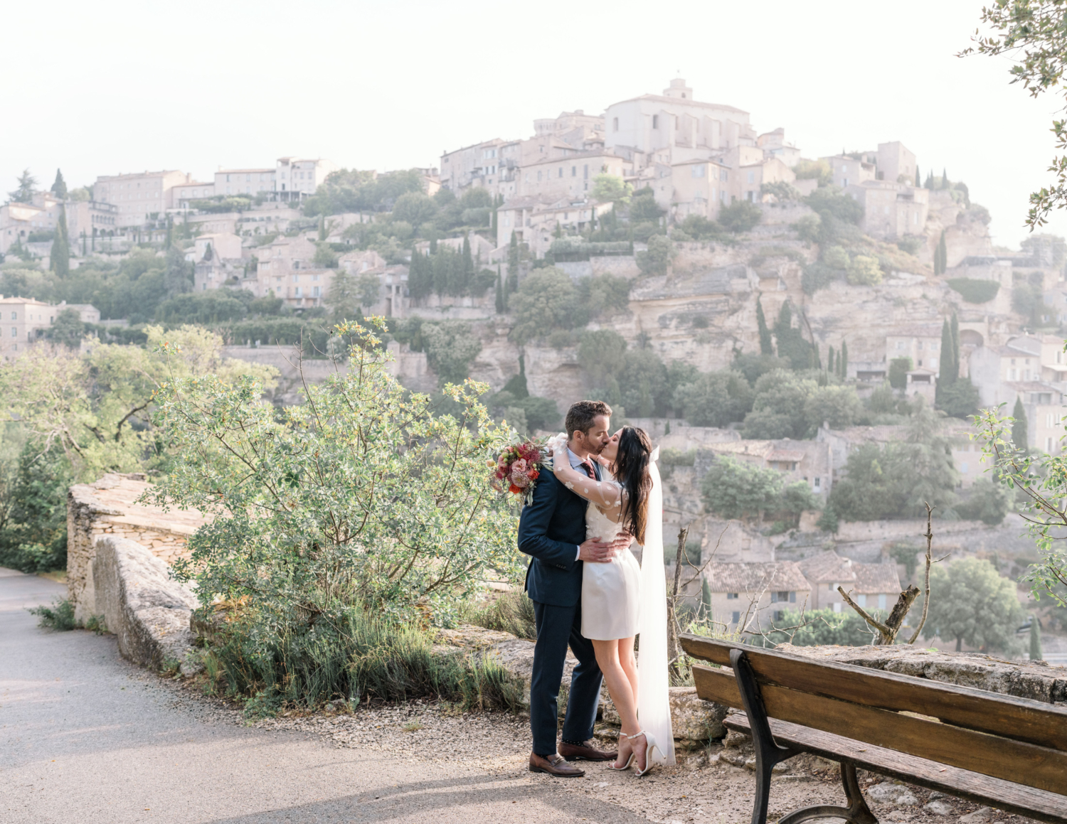 bride and groom passionately kiss with view of gordes france