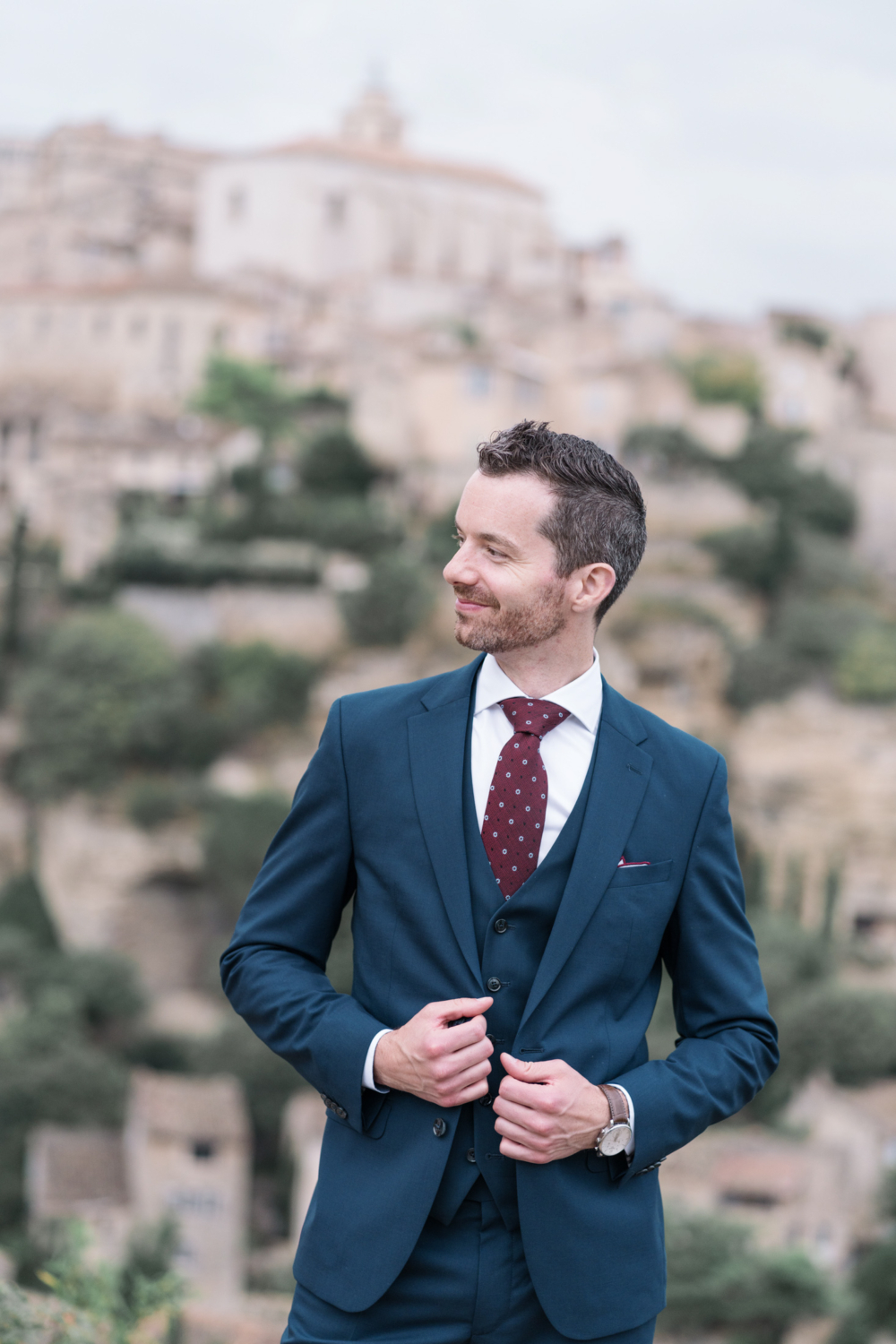 handsome groom poses in gordes france on his wedding day