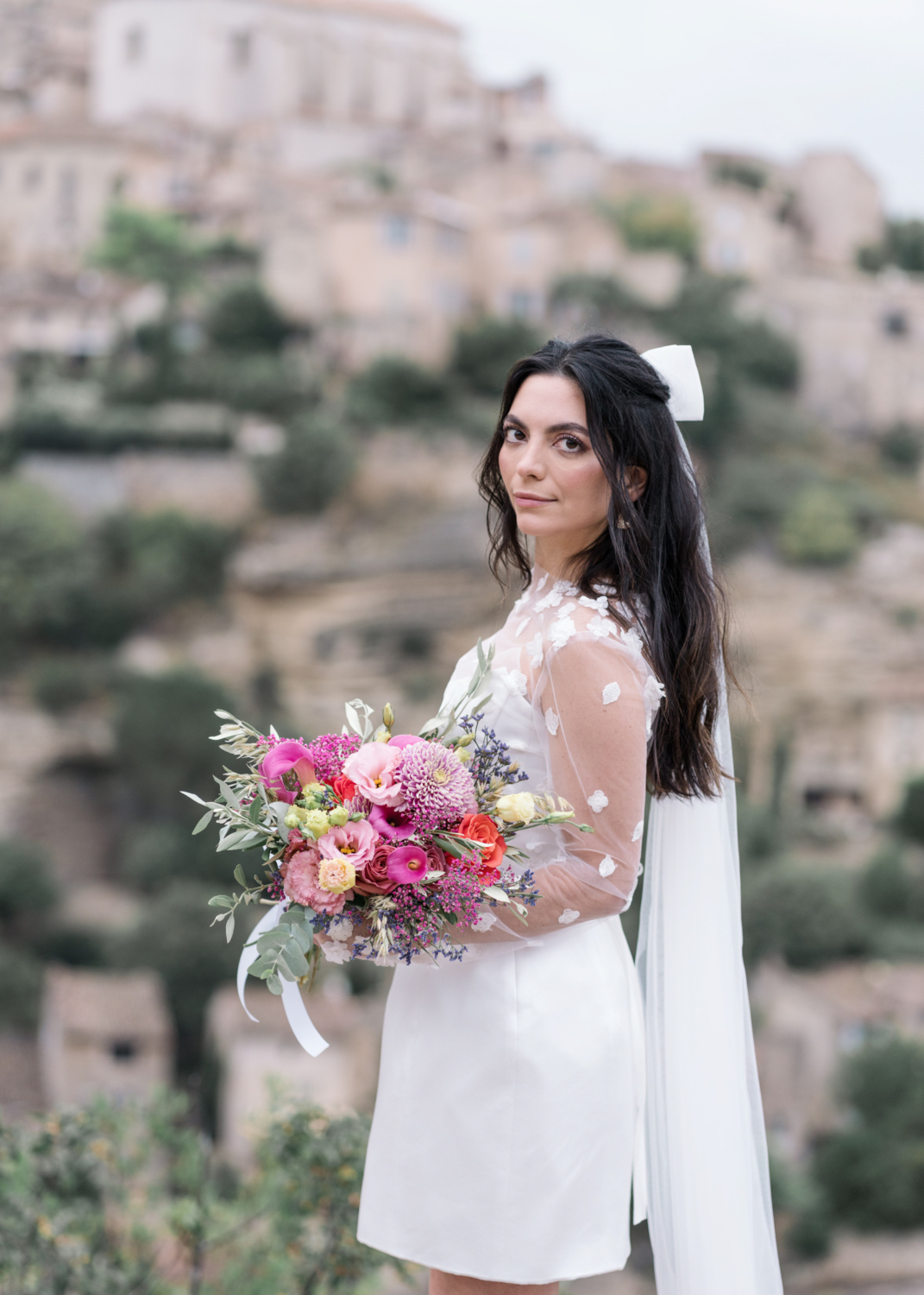 bride poses in gordes france with flower bouquet on her wedding day