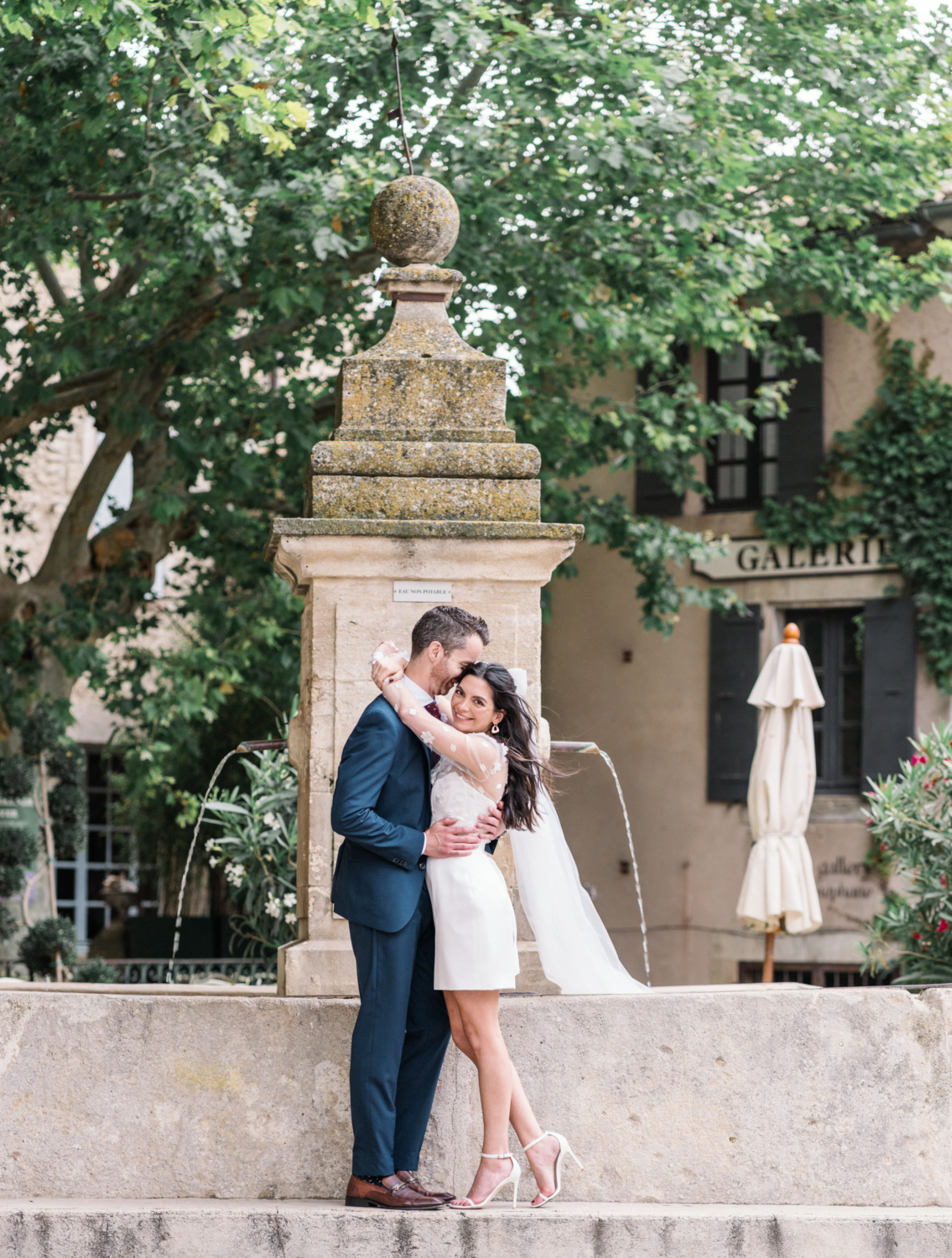 bride and groom embrace at fountain in gordes france