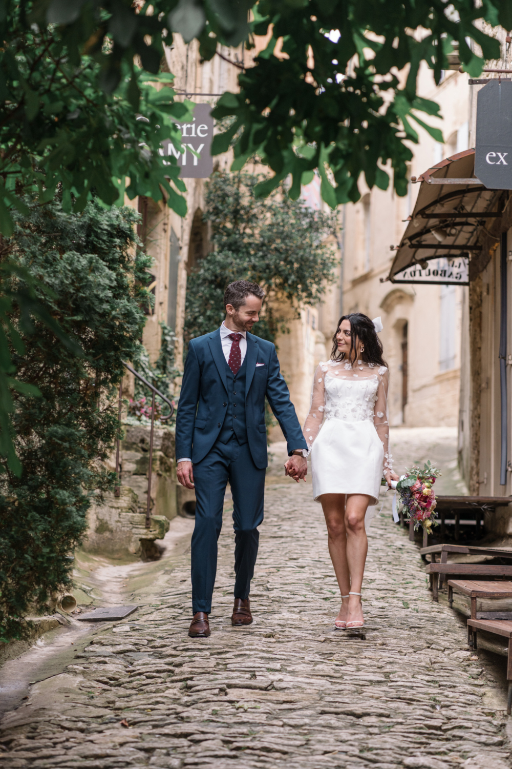 bride and groom walk hand in hand on cobblestones in gordes france