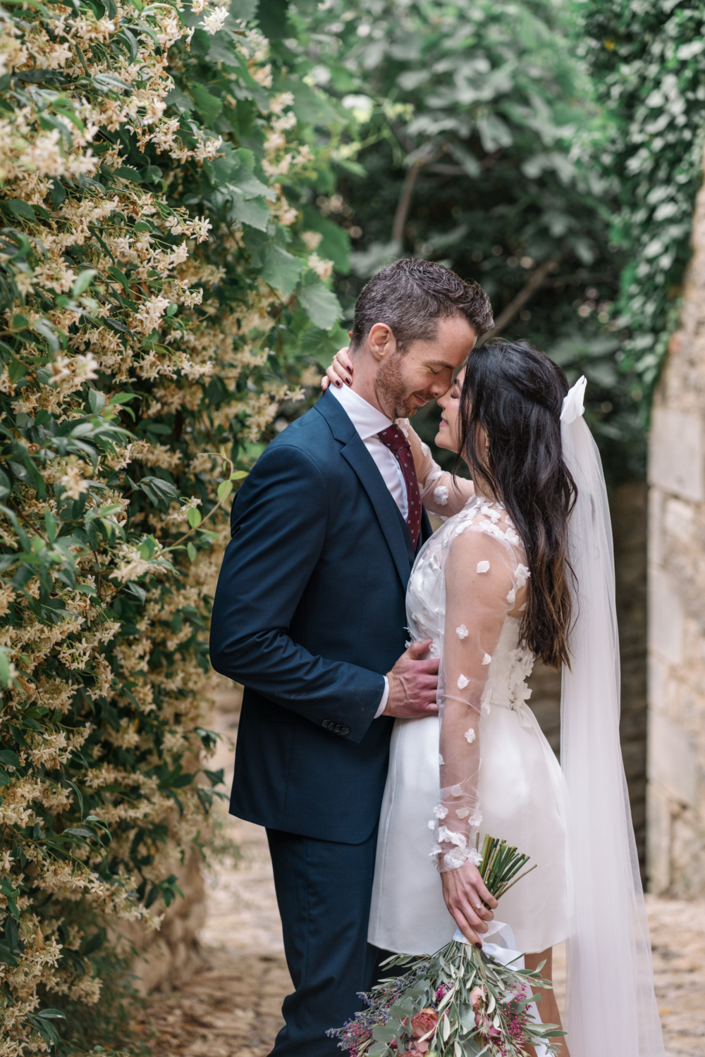 bride and groom get cozy next to jasmine in gordes france