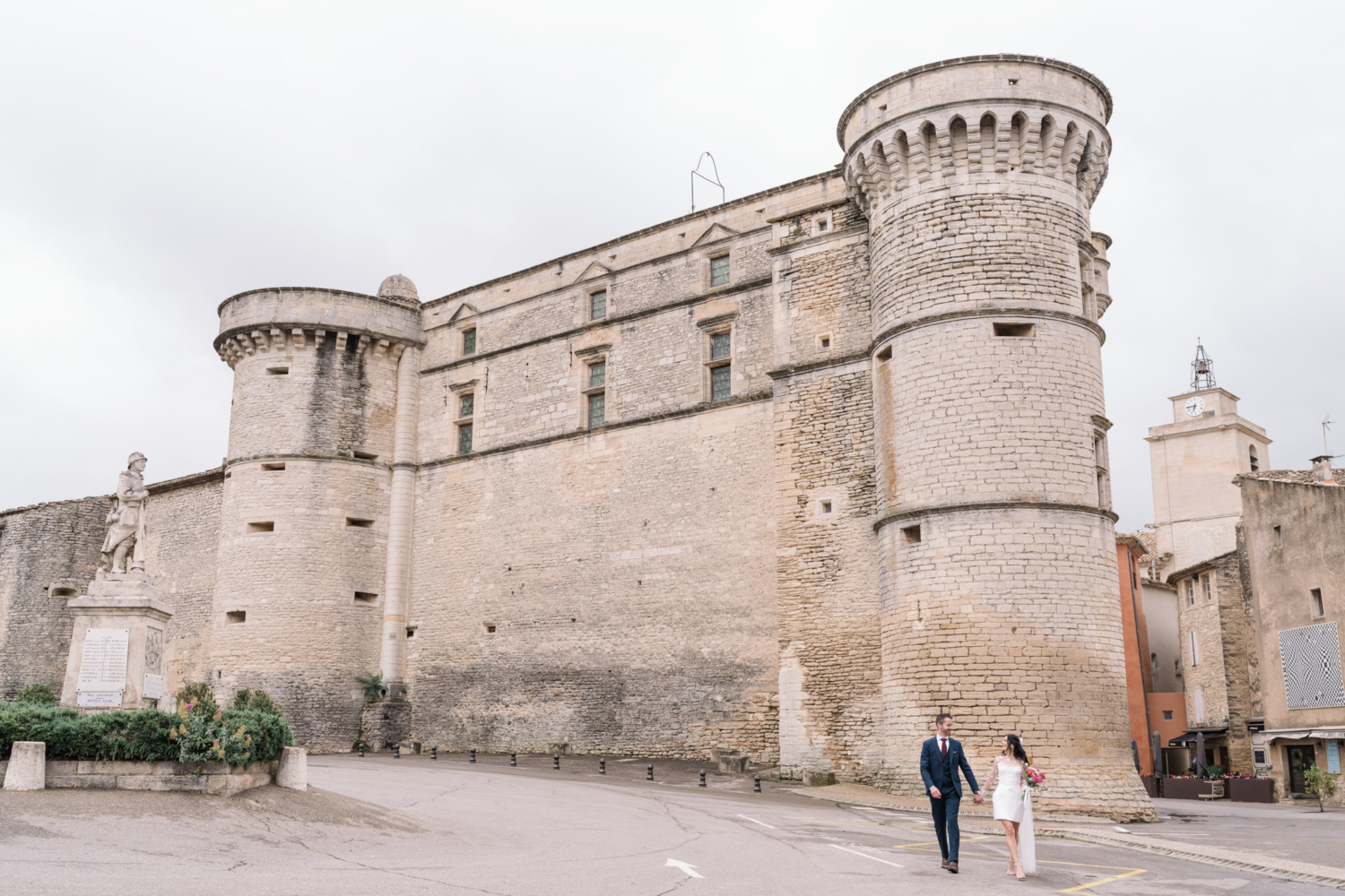 bride and groom walk next to the castle in gordes france