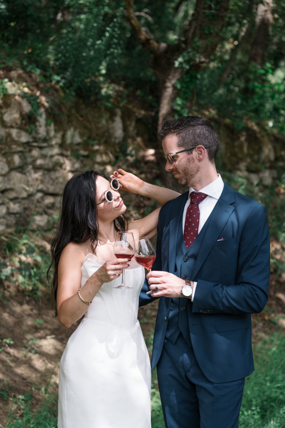 bride and groom wear sunglasses and drink juice after their wedding