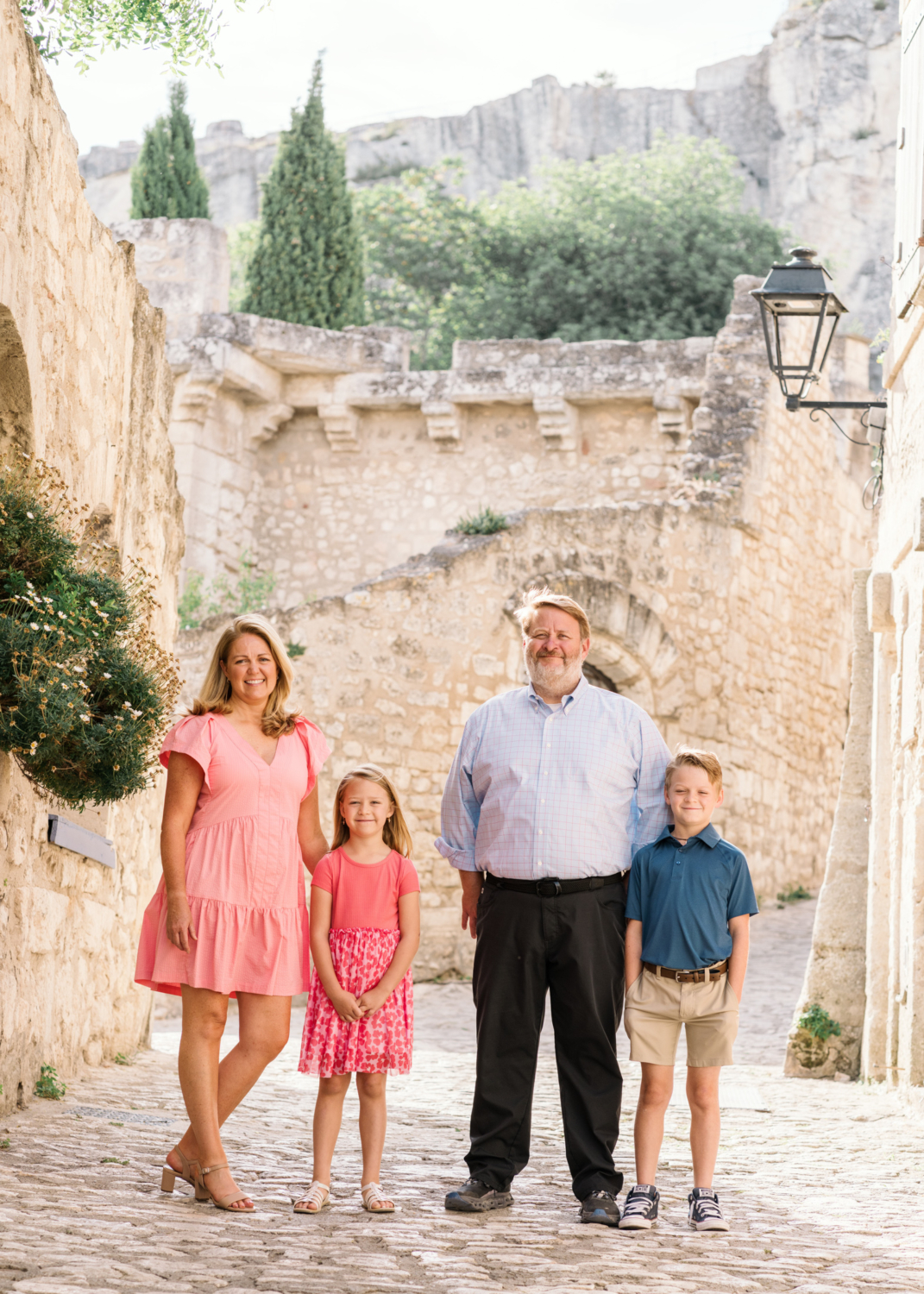 cute family poses in front of medieval city of les baux de provence france