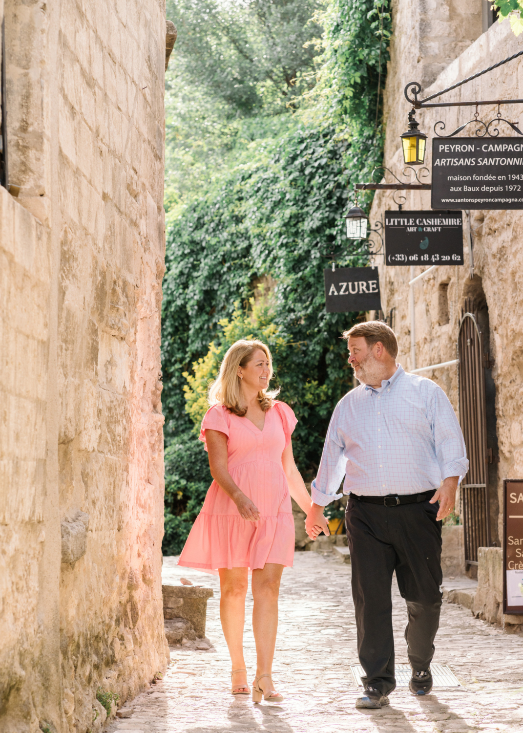 husband and wife walk hand in hand in historic town in france