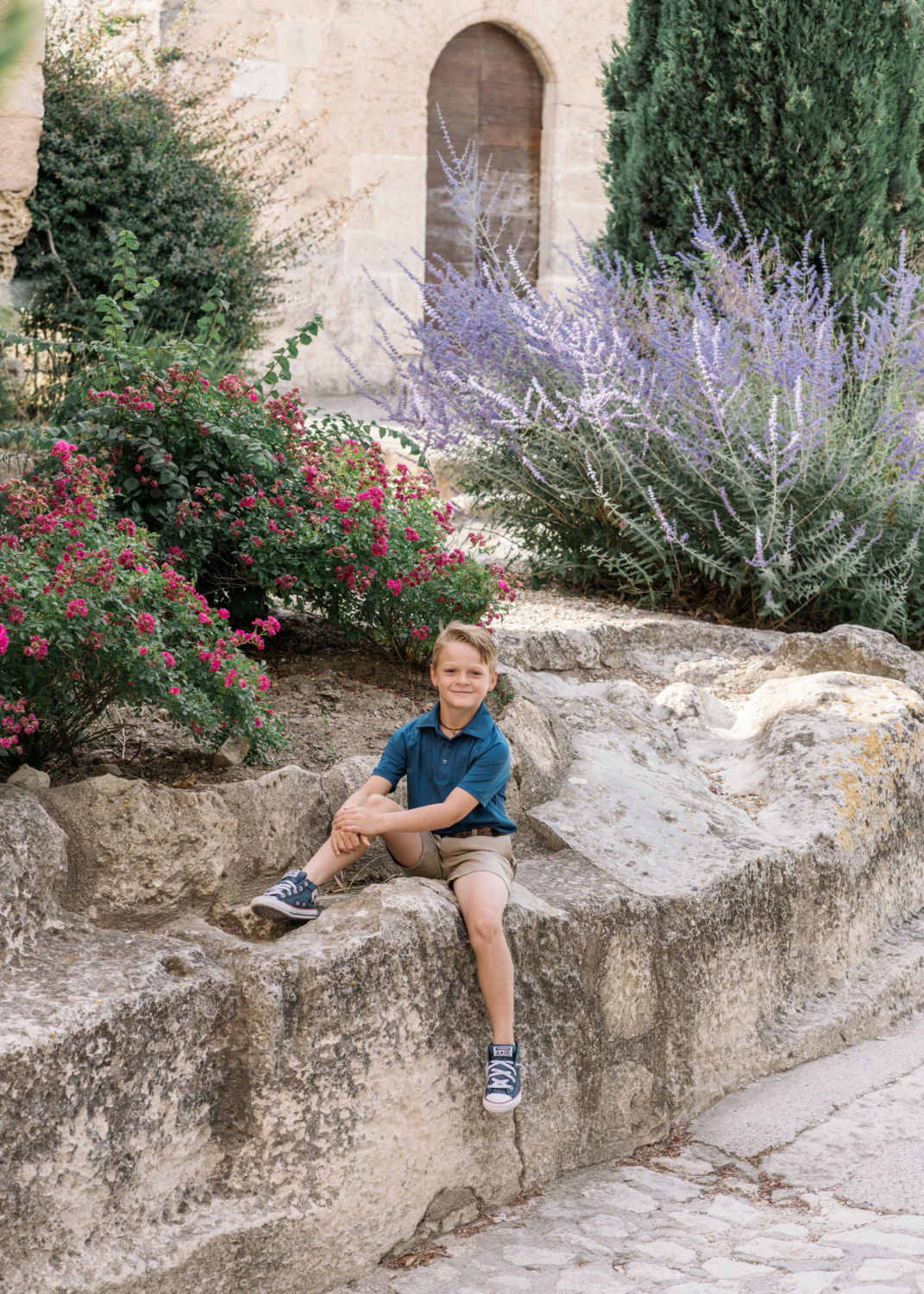 young boy sits on a rock in les baux de provence france