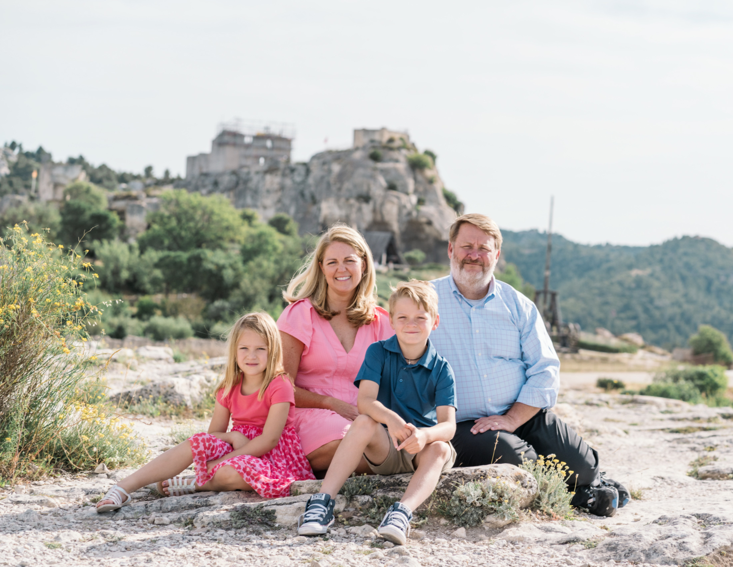 cute family of four pose on a rock in les baux de provence