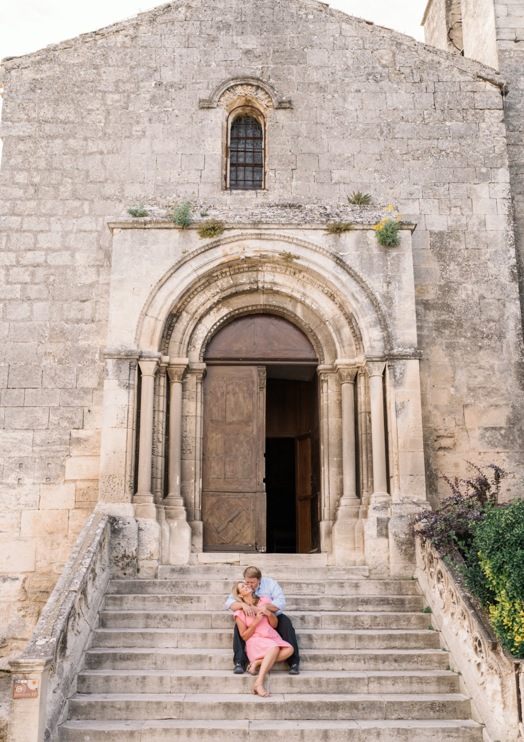 man kisses woman on staircase of church in les baux de provence france