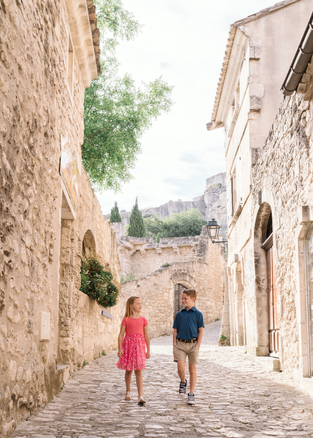 two cute kids walk the cobblestone streets in les baux de provence