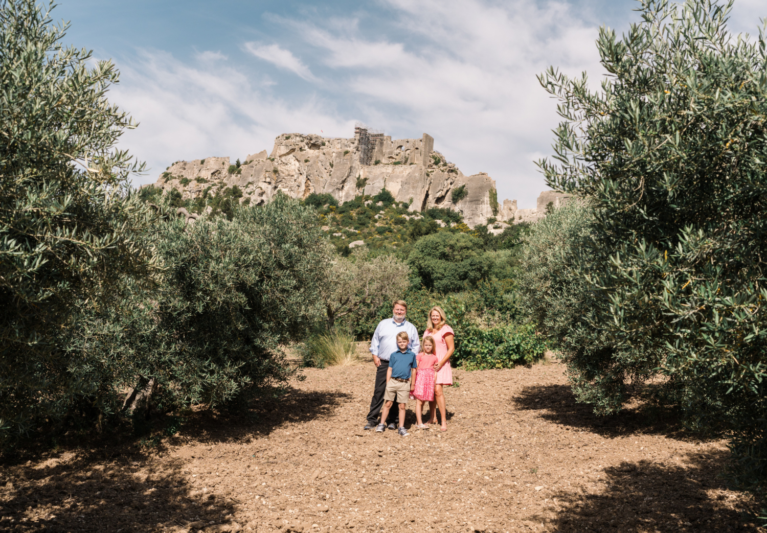 cute family poses in olive grove with mountains in background in les baux de provence france