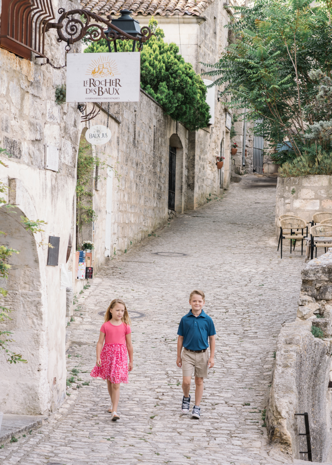 young brother and sister walk together in old town les baux de provence