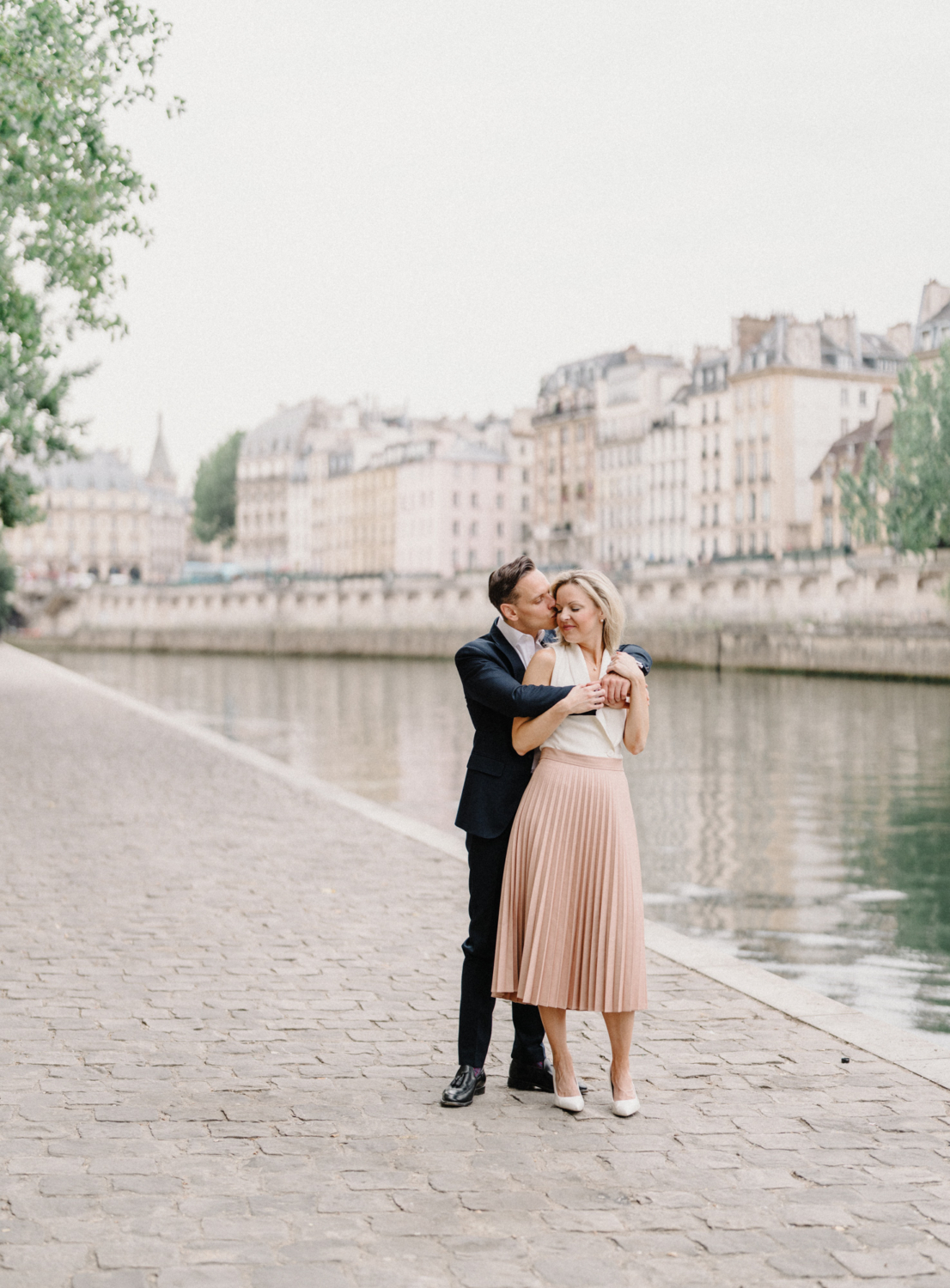 engaged couple embrace along seine river in paris