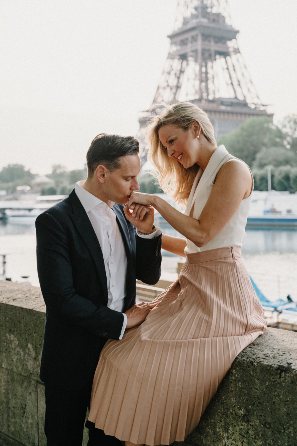 man kisses woman's hand with eiffel tower in background